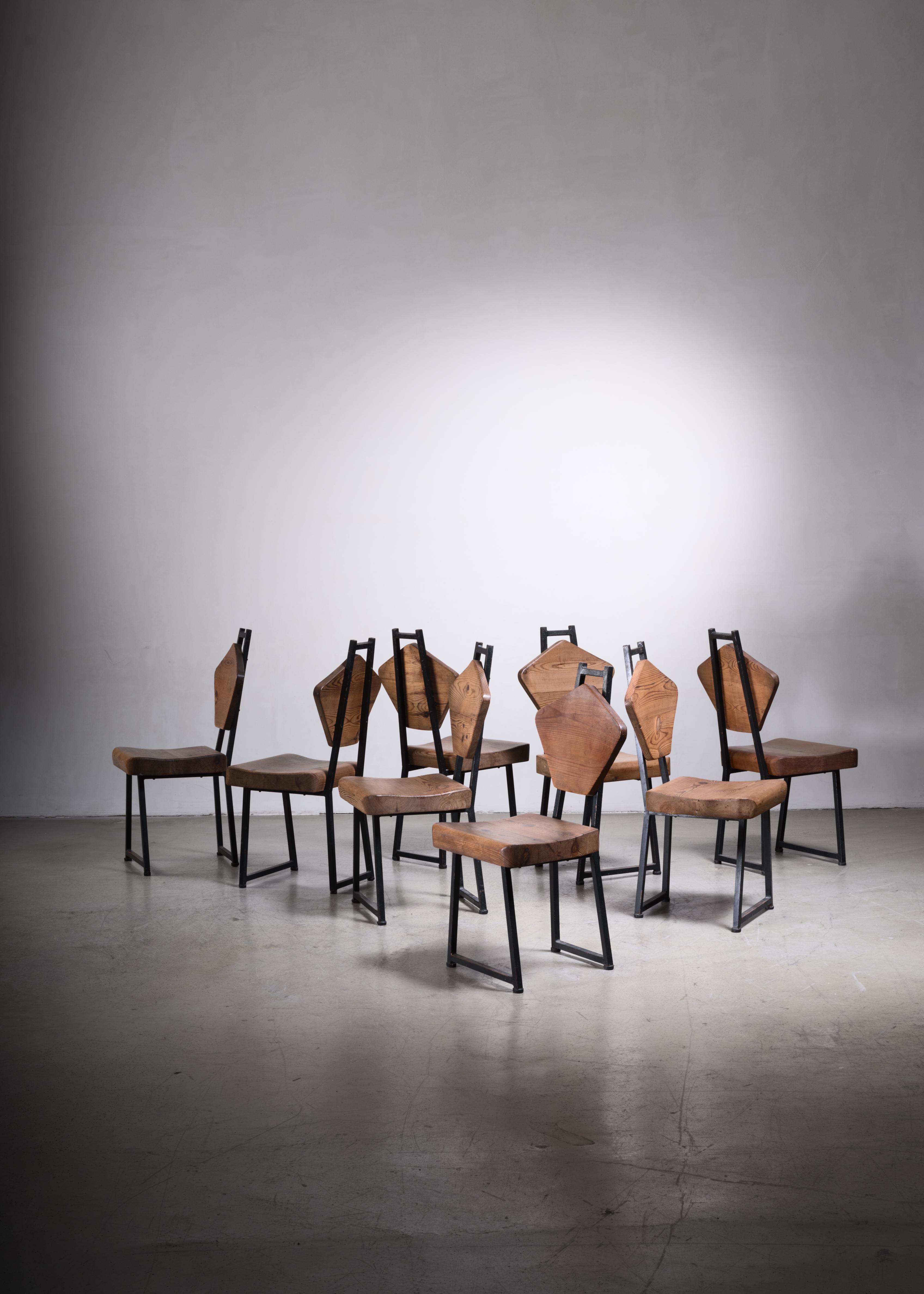 A set of eight Mid-Century Campagne style chairs from France. The chairs are made of a sturdy iron frame with a pentagonal pine backrest and a thick, sculpted pine seating. The wood has beautiful connections, reminiscent of the work of Charlotte