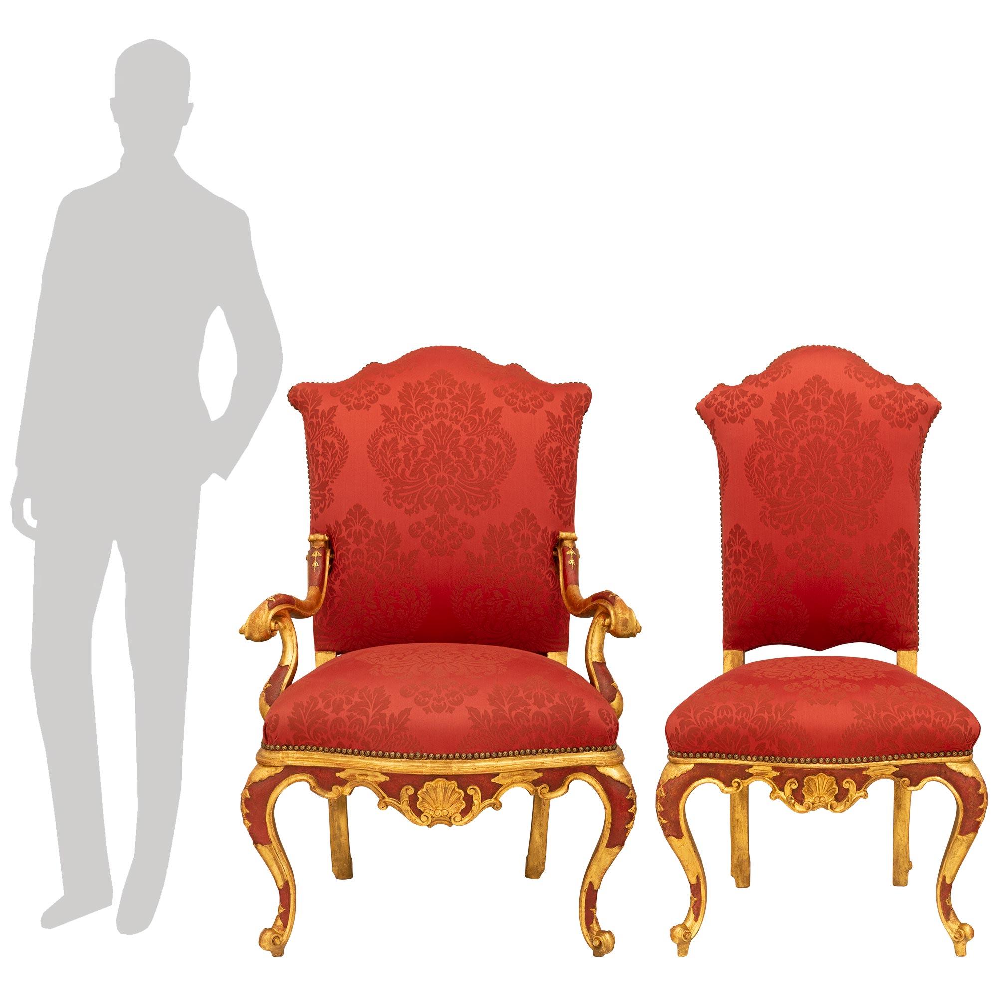 A sensational set of eight Italian mid 18th century Venetian st. red Polychrome and Giltwood dining chairs. The set of six side chairs and two armchairs are elegantly raised on cabriole legs decorated by a central gilt crest below a cartouche with