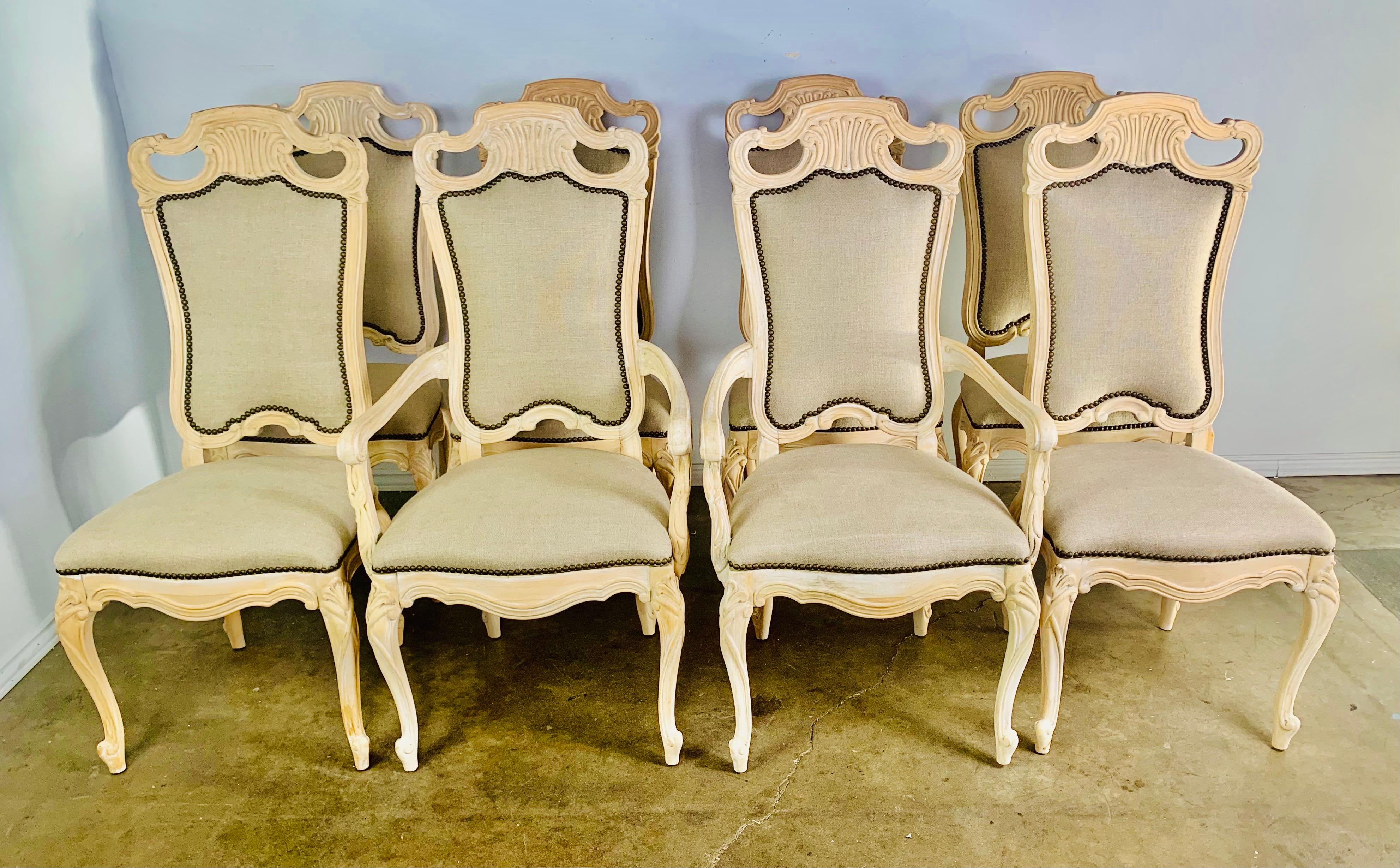 Set of eight French natural carved wood dining chairs. The chairs stand on four cabriole legs with rams head feet. The chairs are newly upholstered in a washed Belgium linen with nailhead trim detail.

Armchair size: 23
