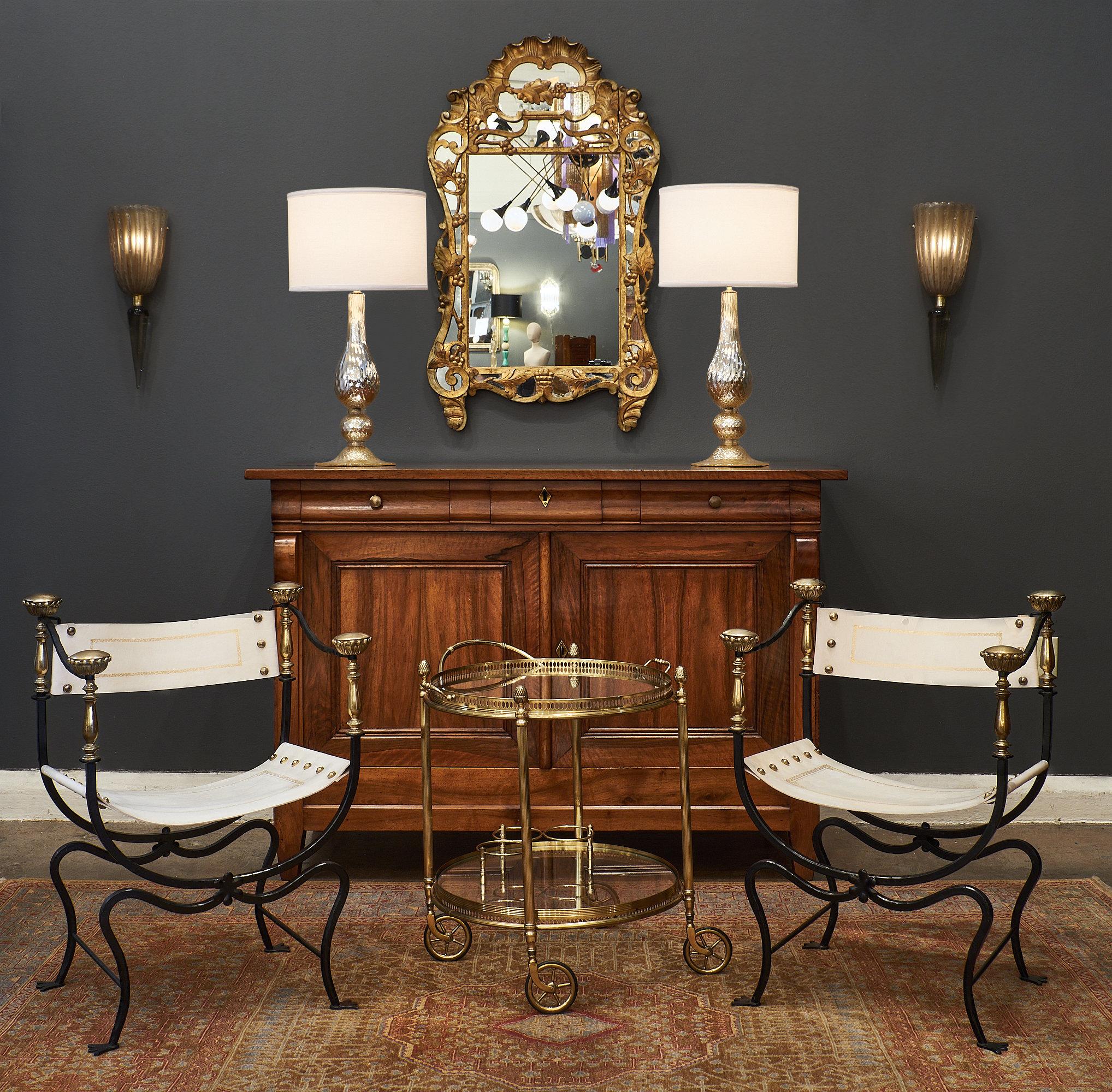 A rare and important set of eight Italian Renaissance style Savonarola armchairs of hand-hammered iron featuring gilt embossed leather seats. We loved the floral details on the finials, the brass nailheads, and the overall decorative impact of the