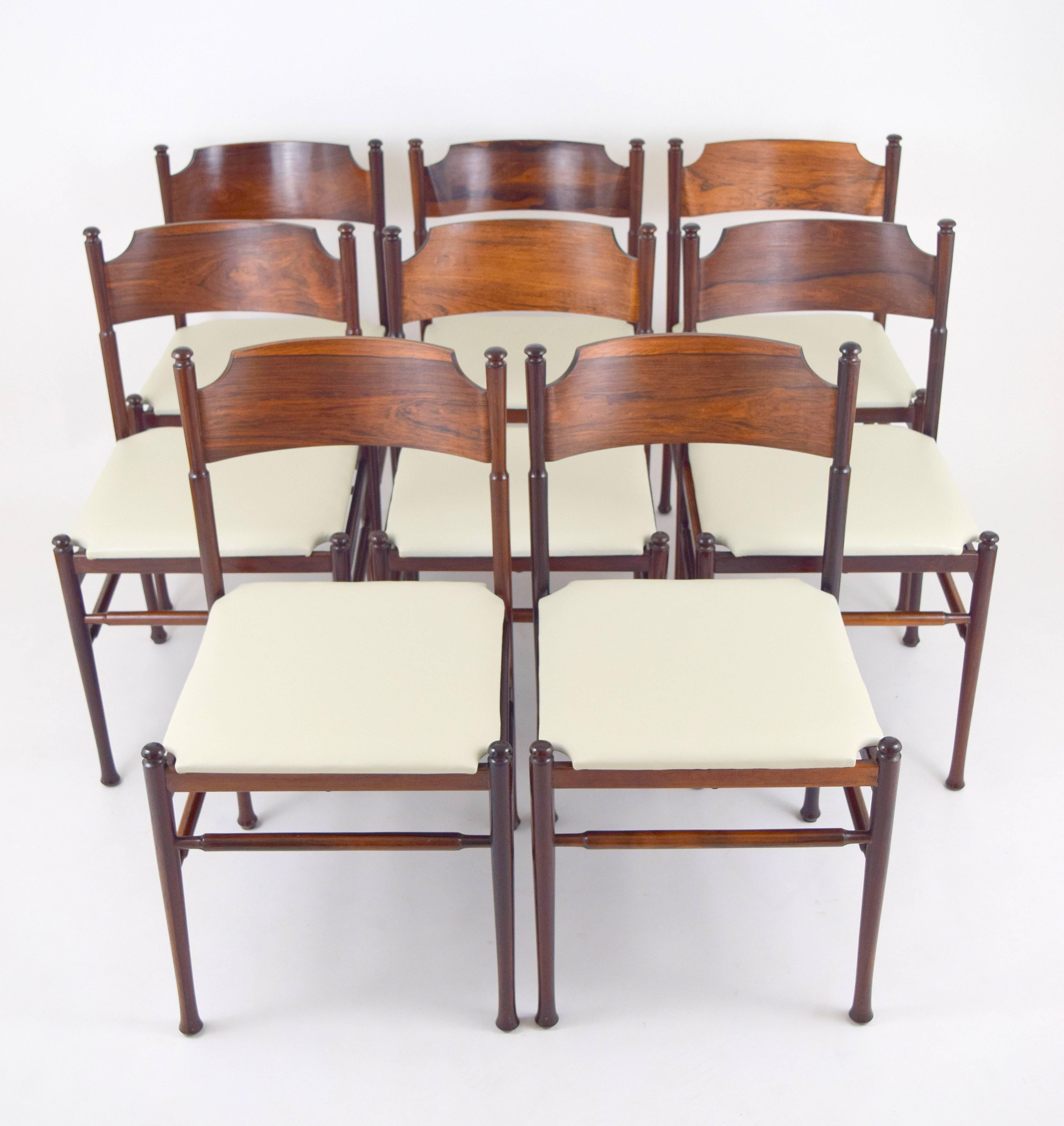 Elegant set of eight rosewood dining chairs in the manner of Osvaldo Borsani. Delicate and light in scale with turned elements and curved plywood backs. Each has a handmade quality with slight variations in wood thickness on backs. Newly upholstered