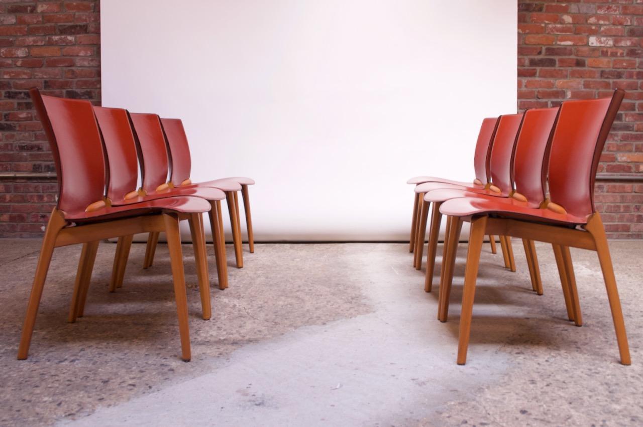 Set of eight leather and beech dining chairs designed in 1994 by the Spanish designer, Josep Llusca, for Cassina, (Italy).
Features a red leather frame supported by deeply sculpted beech legs / base. The leather is molded around the beechwood where