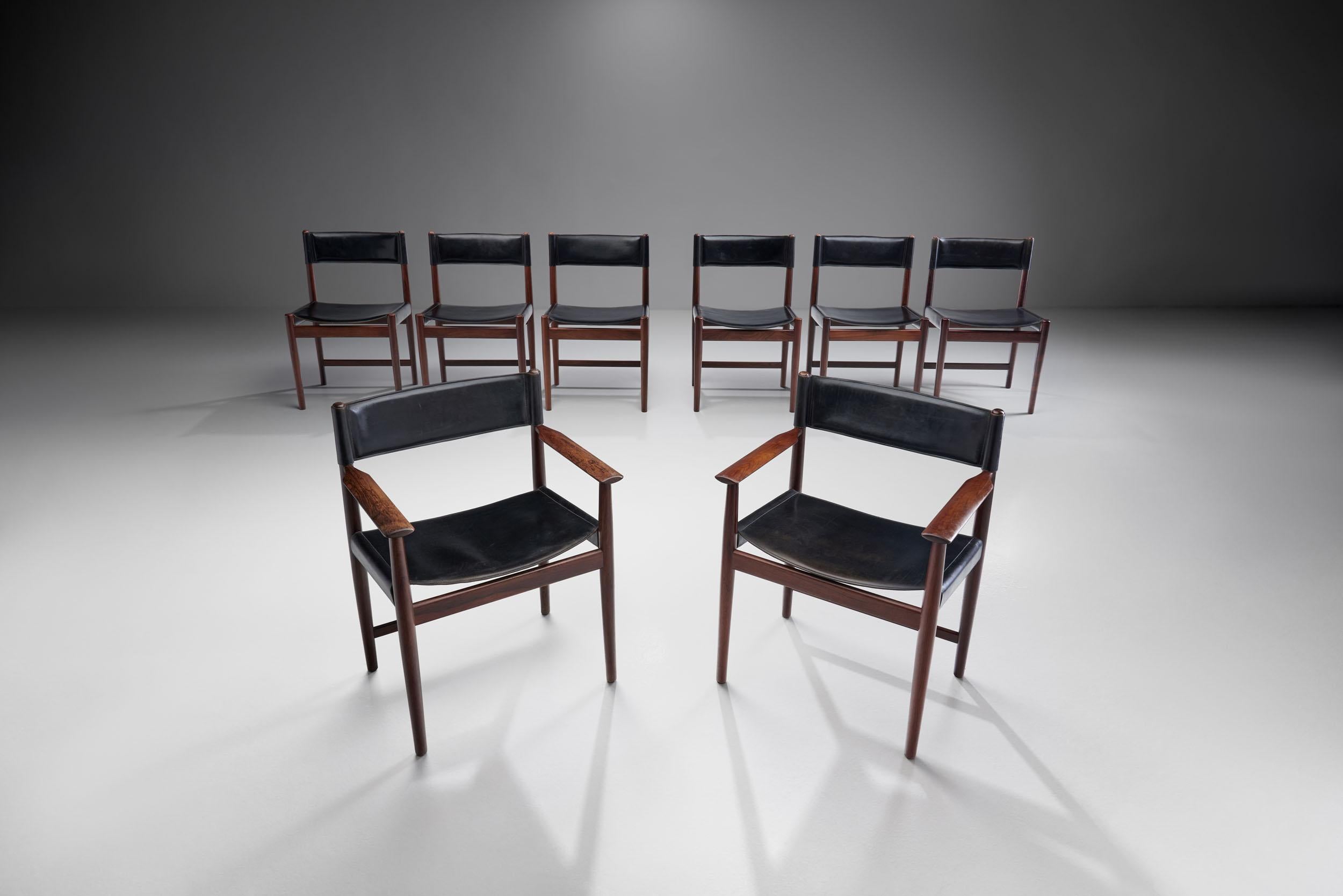 This set of eight dining chairs by Danish designer Kurt Østervig is a beautiful example of simple, refined midcentury Danish design.

The black leather chairs are made of wood, with a dark color. The deep color of the wood and the upholstery create