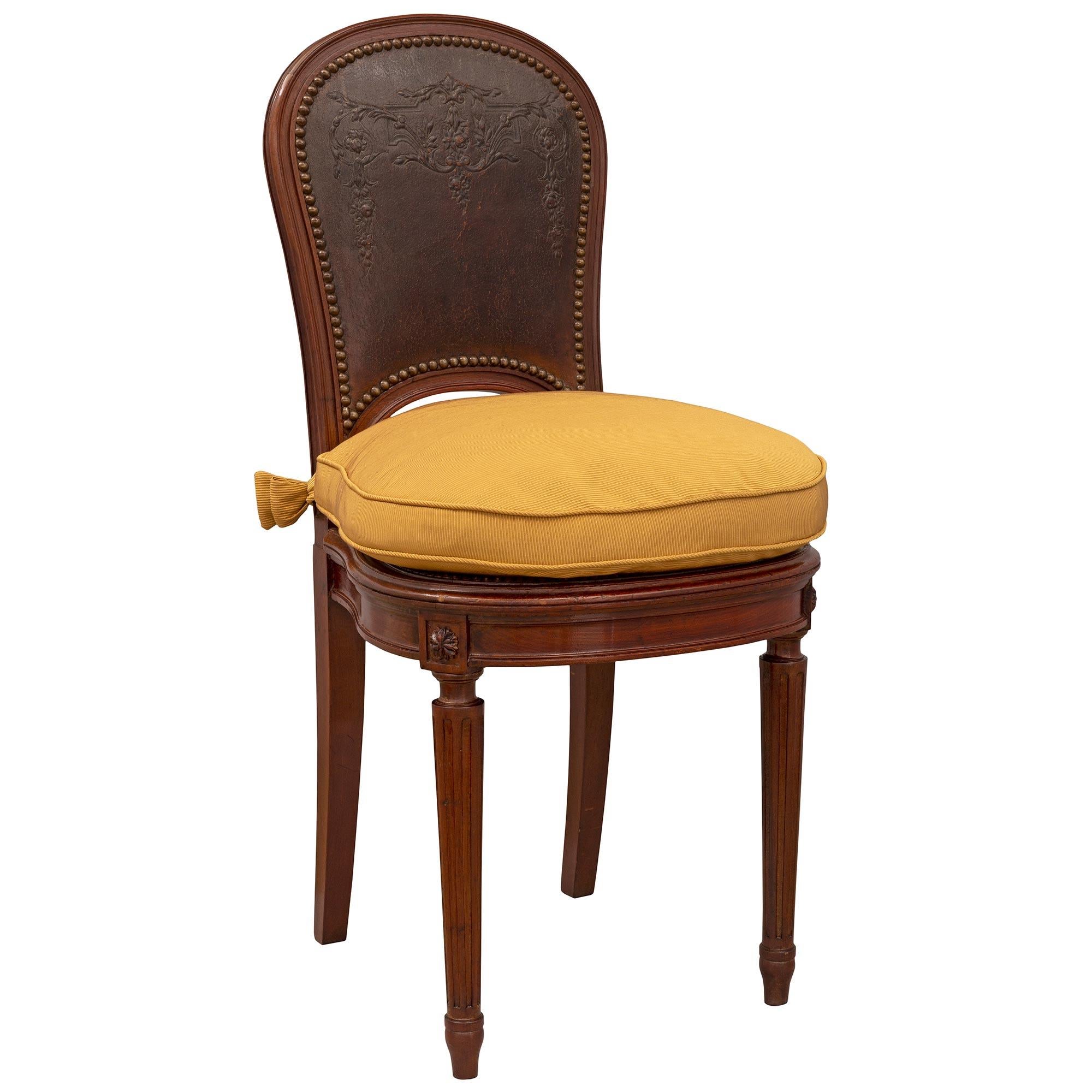A most attractive complete set of eight French 19th century Louis XVI st. mahogany and pressed leather chairs. Each chair is raised by elegant circular fluted tapered legs with fine topie shaped feet. Above each leg are richly carved block rosettes