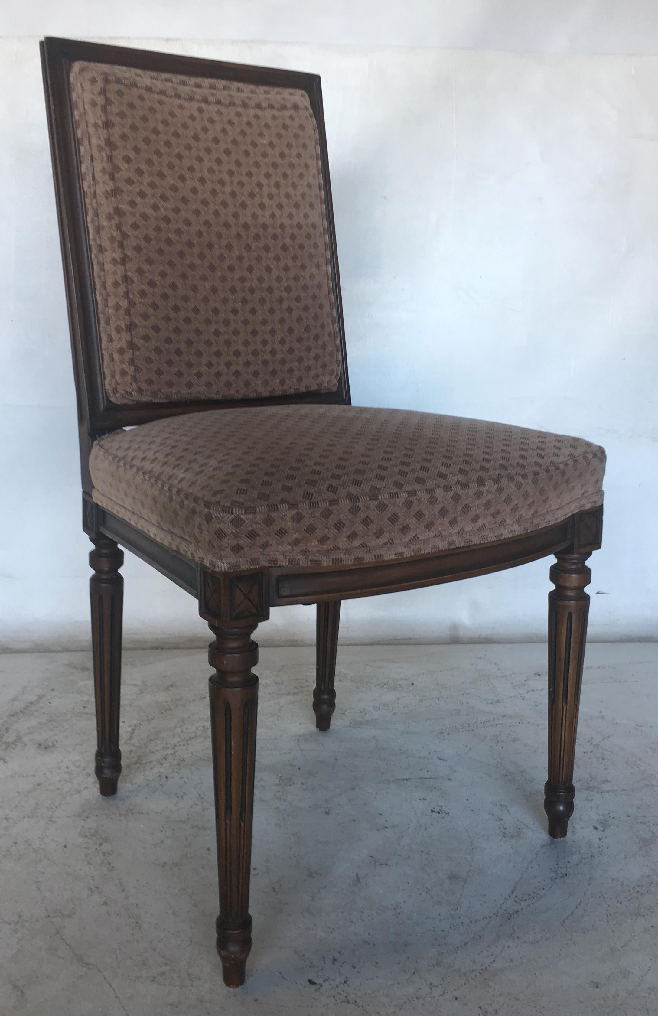 Beautifully rendered set of eight Louis XVI style dining chairs with their original upholstery. The simply but handsomely adorned chairs have a minimum of carving aside from their fluted legs with a simple 