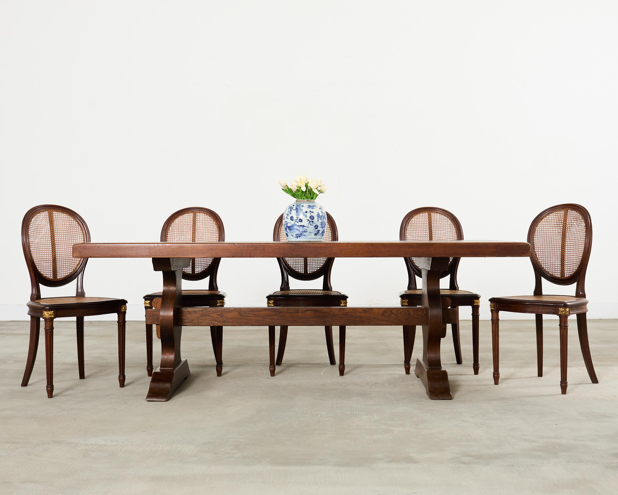 Divine set of eight French mahogany dining chairs made in the grand Louis XVI taste. The set features rich, radiant mahogany frames with hand-caned oval balloon backs and seats. The chair aprons are embellished with bronze ormolu rosettes in the