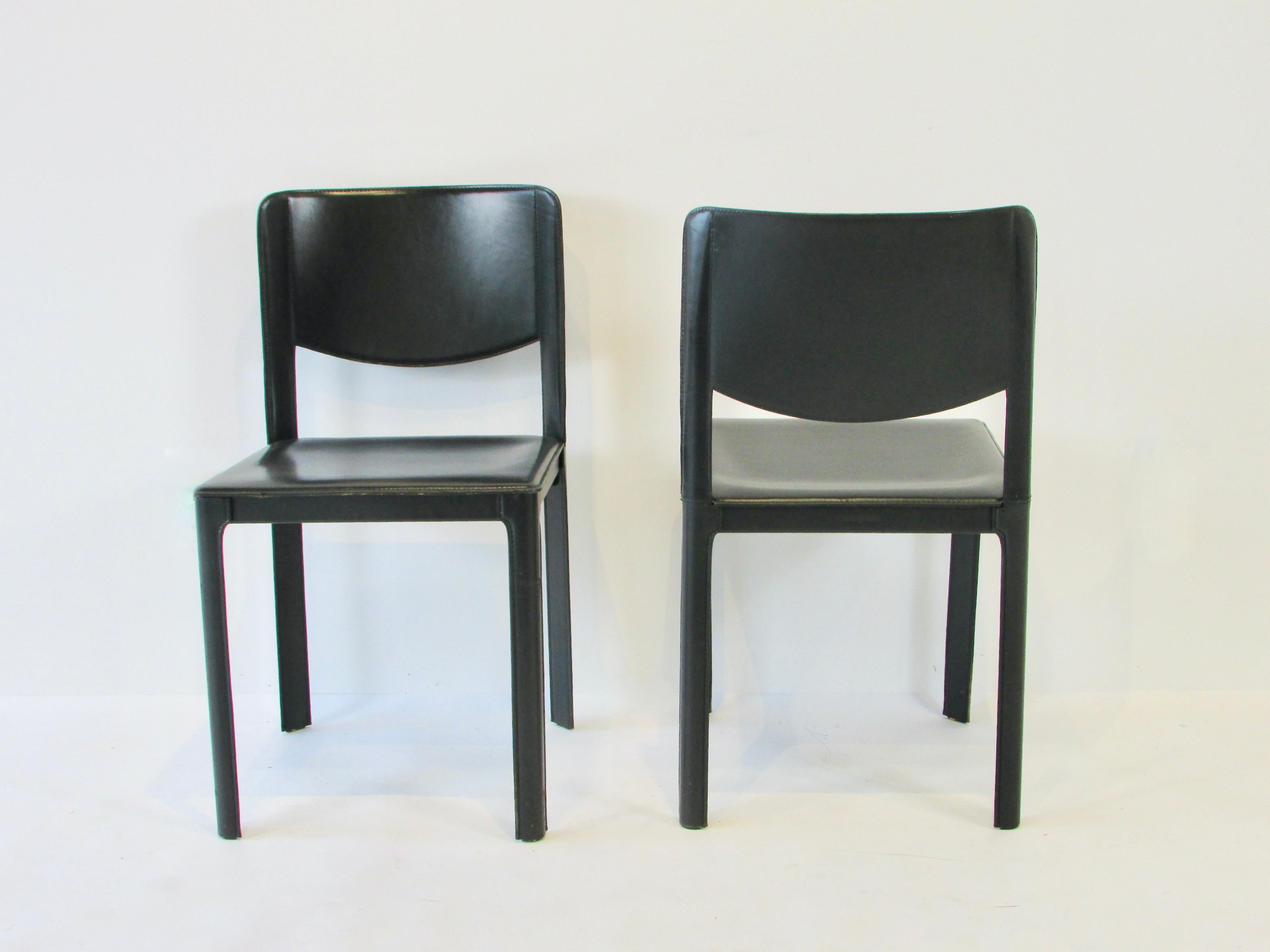 Eight dining chairs by Matteo Grassi . Chairs are covered in saddle thick black leather over a steel frame . Marked Matteo Grassi on underside , incised stamp on rear cross stretcher .  