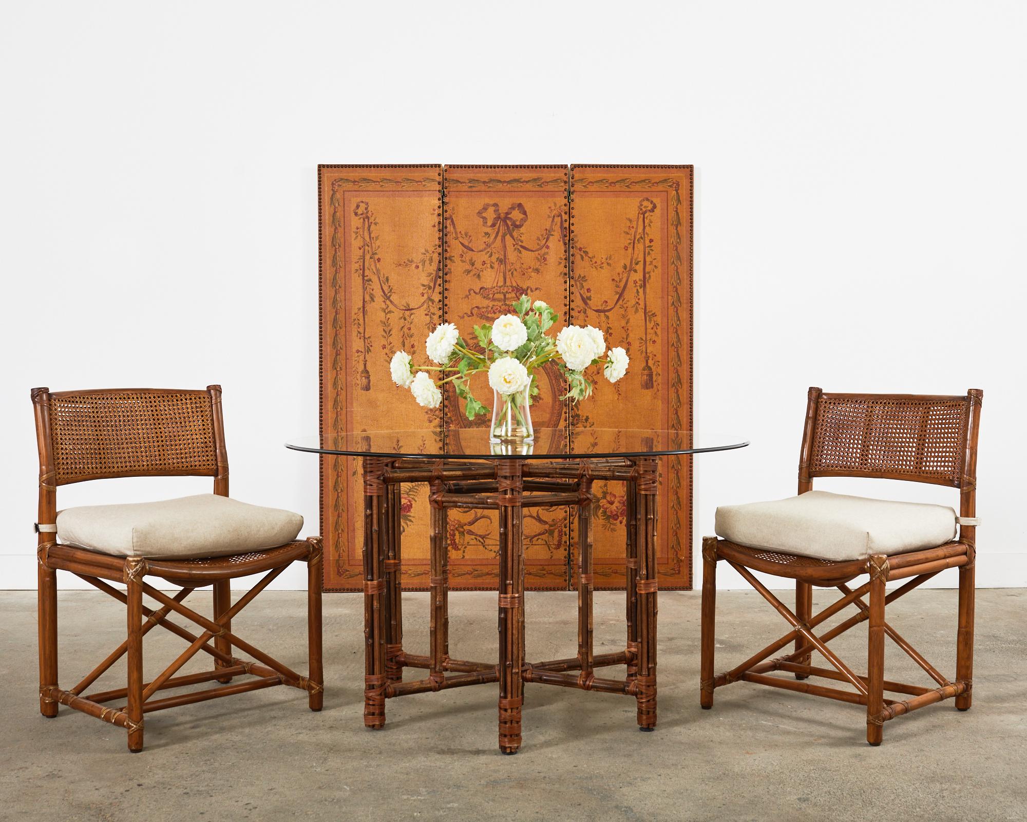 Rare set of eight genuine McGuire rattan dining chairs made in the California coastal organic modern style. The set features generous rattan frames in a directors chair style with straight legs conjoined by x form stretchers. The chairs have a