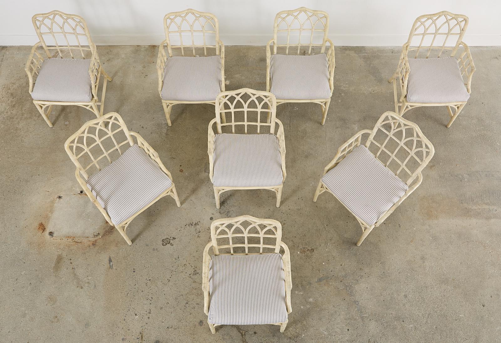 Distinctive genuine set of eight rattan dining armchairs made in the California organic modern style by McGuire. Crafted from rattan poles the frames have a gothic lancet arch cathedral design on the backs and an open fretwork on the sides in a