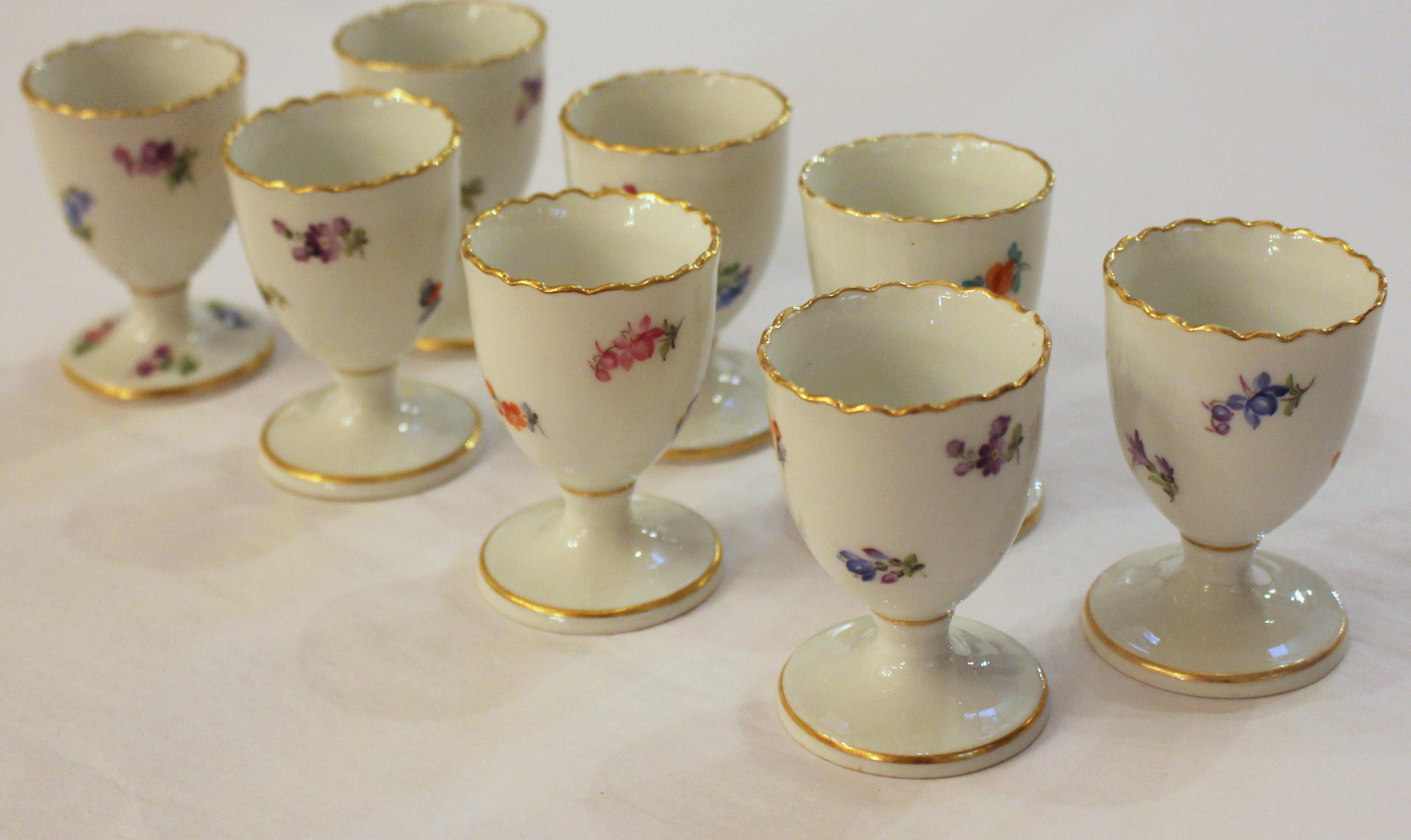 Juego de 8 hueveras de Meissen con motivos de flores esparcidas o streublumen. Bordes dorados (pequeños roces). Espadas cruzadas marca Meissen. c.1860-1920. 1 con pequeño desconchón en la parte superior de la base y otro debajo. 3 con pequeños