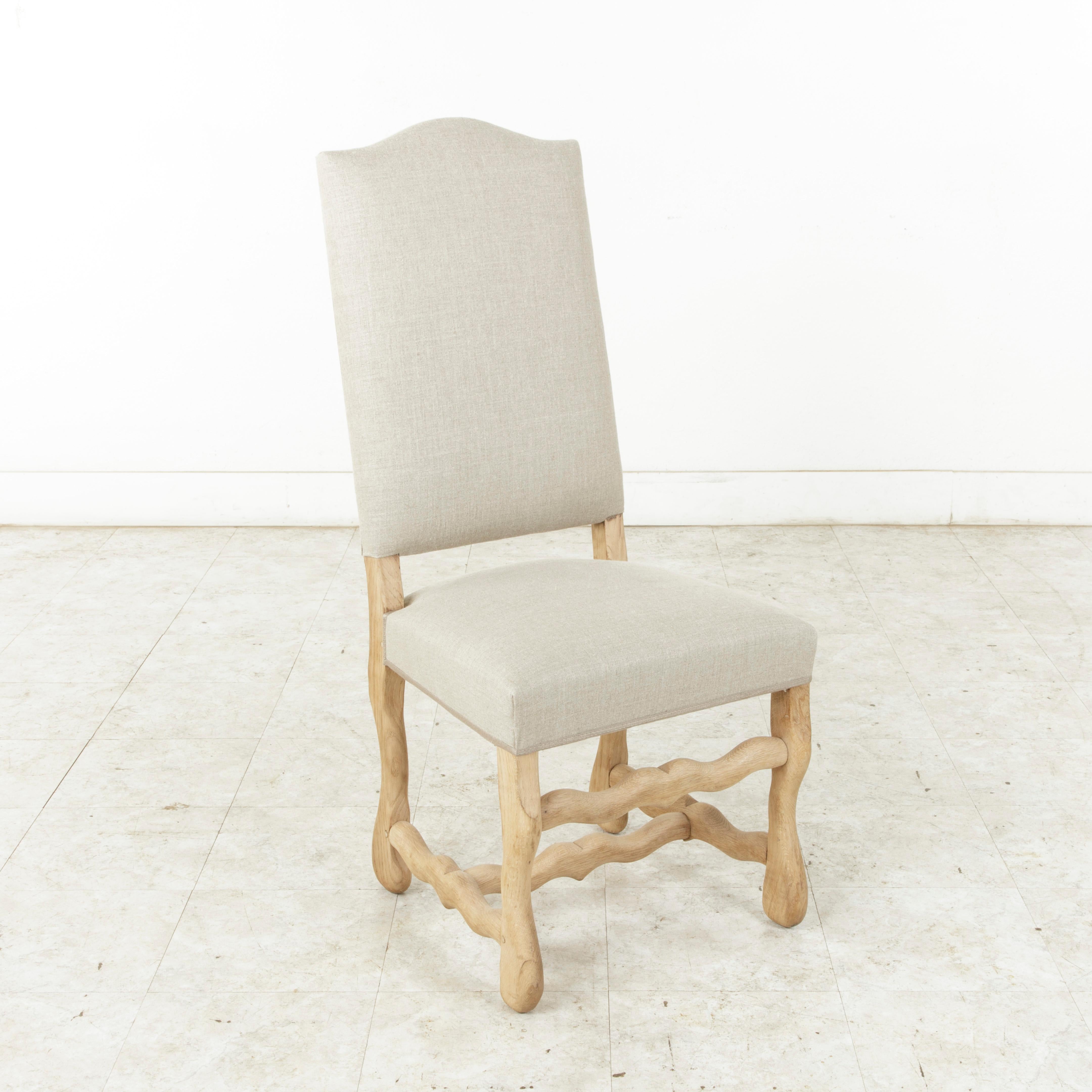 Newly upholstered in France in a beautiful neutral colored linen, this set of eight mutton leg dining chairs features sturdy hand pegged construction, providing stability to the frame. The unfinished oak and natural linen lend a light, airy feel to