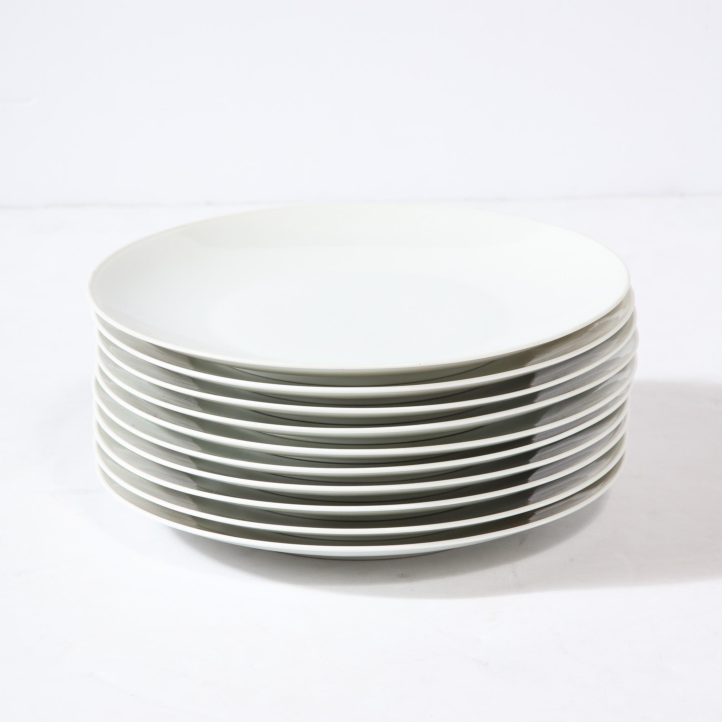 This lovely set of Eight Porcelain Dinner Plates is by the esteemed manufacturer Rosenthal and originates from Germany circa 1960 . Featuring a round profile with gradual slanted edge leading to the center of each piece, these are highly minimal and