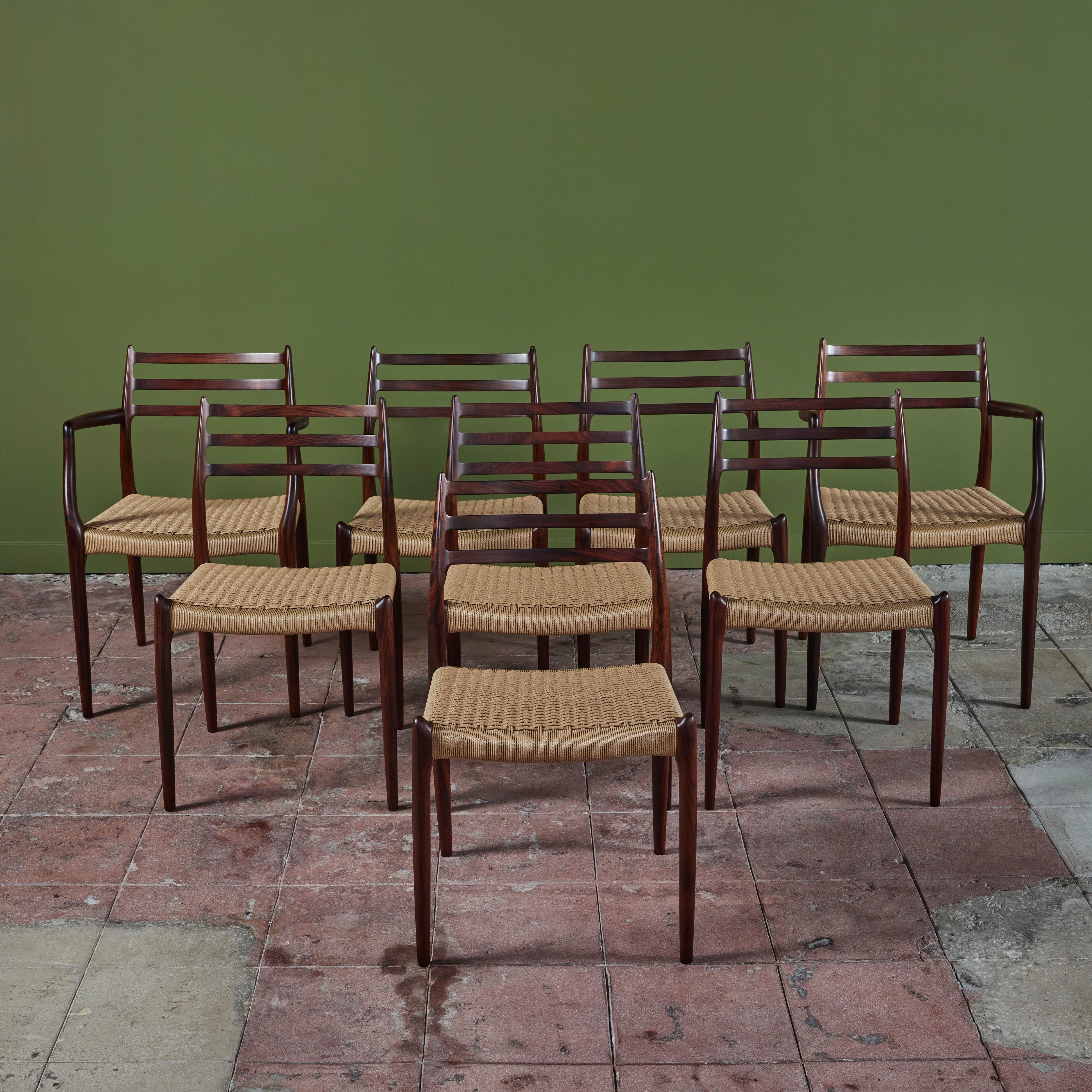 A set of eight rosewood dining chairs designed by Niels Otto Møller in 1962 and manufactured by JL Møllers Møbelfabrik of Denmark with Danish [paper] cord seats. The chairs have a curved backrest with three horizontal supports, terminating in a