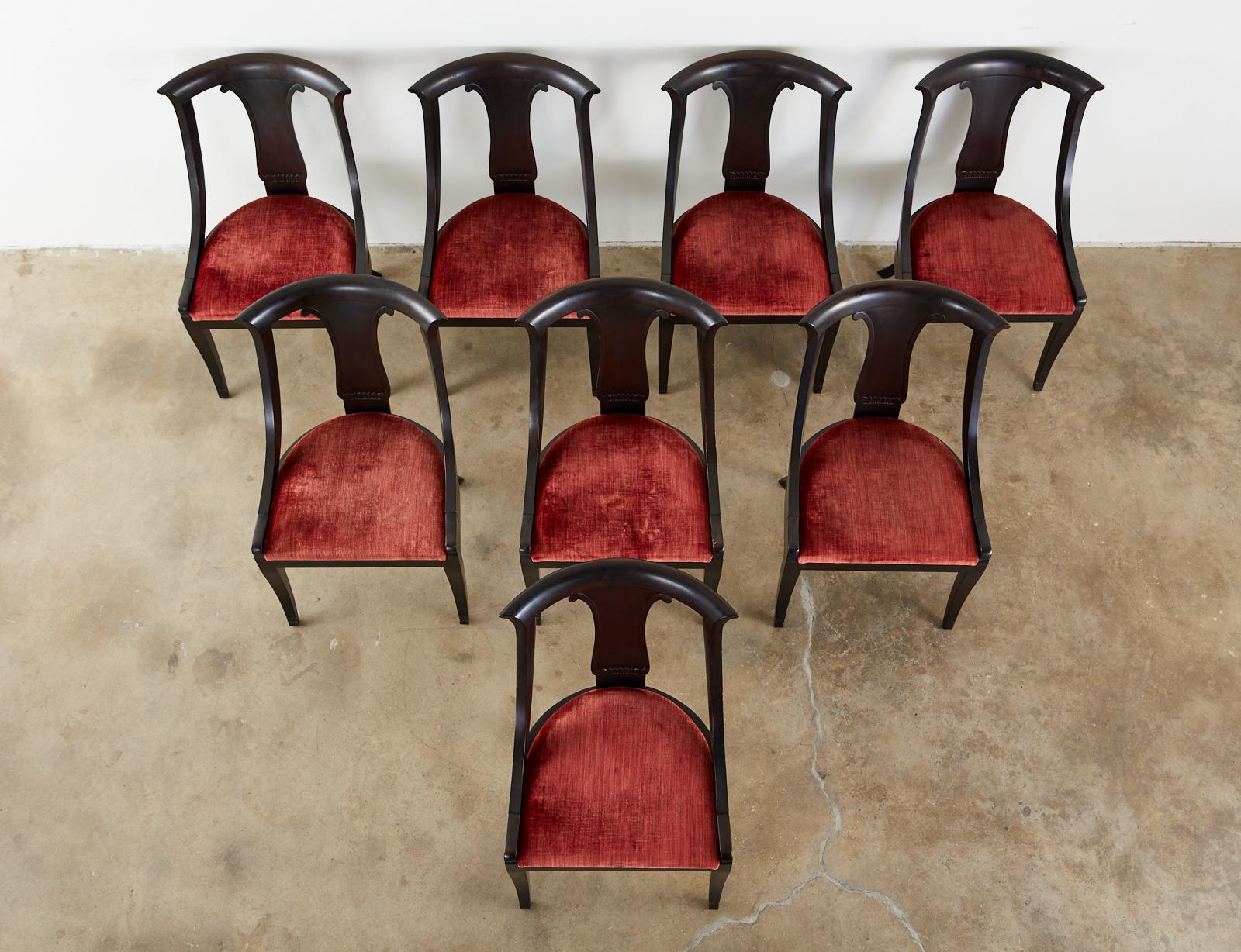 Extraordinary set of eight ebonized mahogany dining chairs featuring a tub or gondola form frame. Made in the neoclassical directoire French taste. Minimally decorated having a vasiform back splat surmounted by a curved crest rail. Gracefully curved
