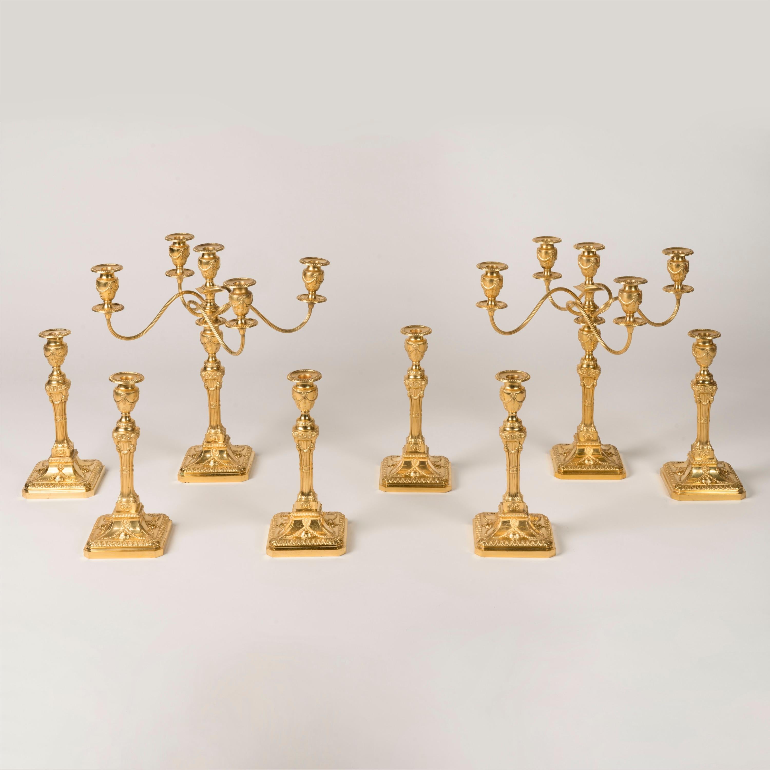 Un set di otto candelieri neoclassici
Con componenti convertibili

Un grande set di otto candelabri in metallo dorato con una coppia di attacchi per candelabri rimovibili che comprendono cinque candelabri ciascuno, progettati nello stile neoclassico