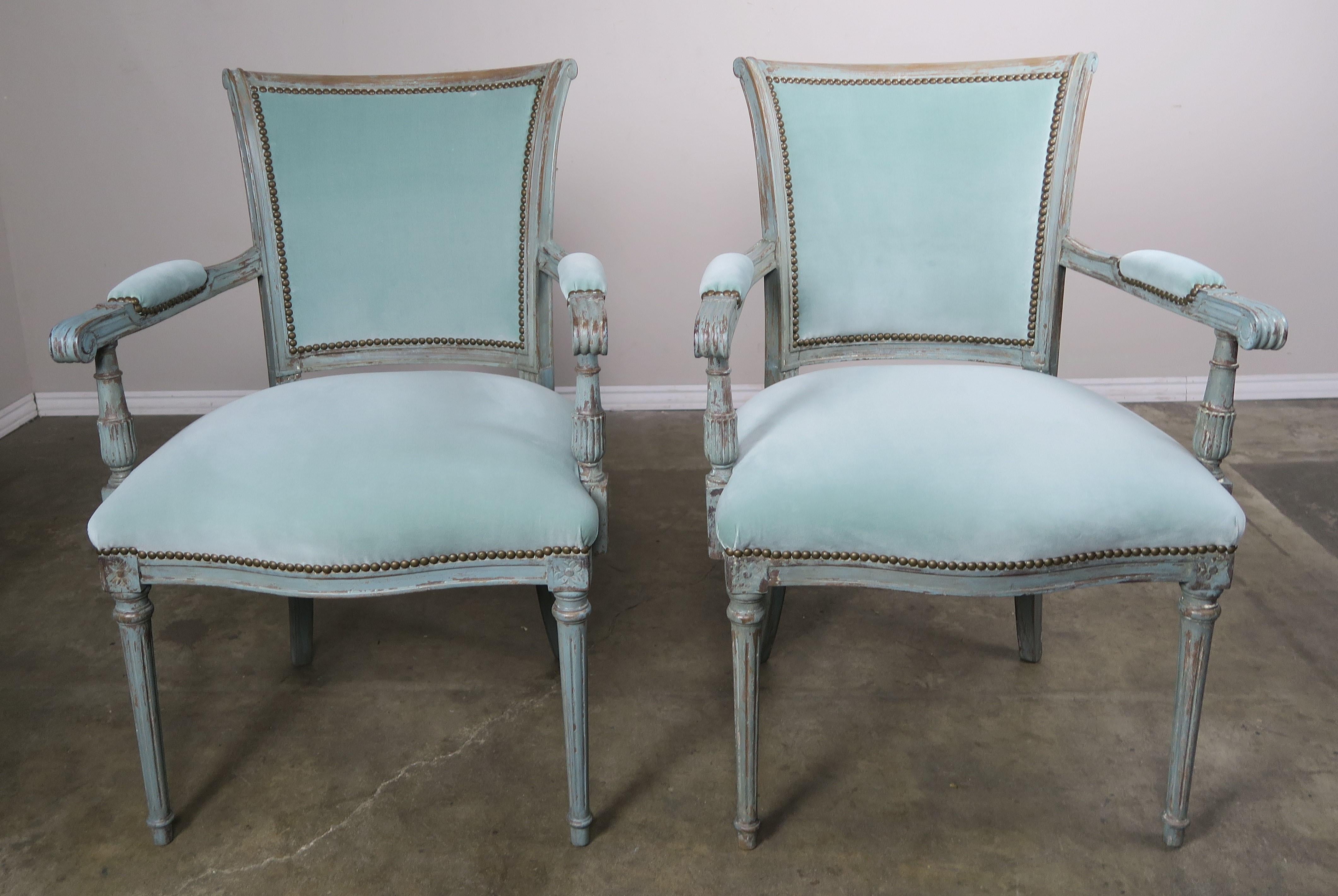 Set of eight painted Louis XVI style dining chairs newly upholstered in soft robin's egg blue velvet with antique brass nailhead trim detail. Each dining chair stands on four fluted straight legs and the chairs have elegant clean lines. The finish