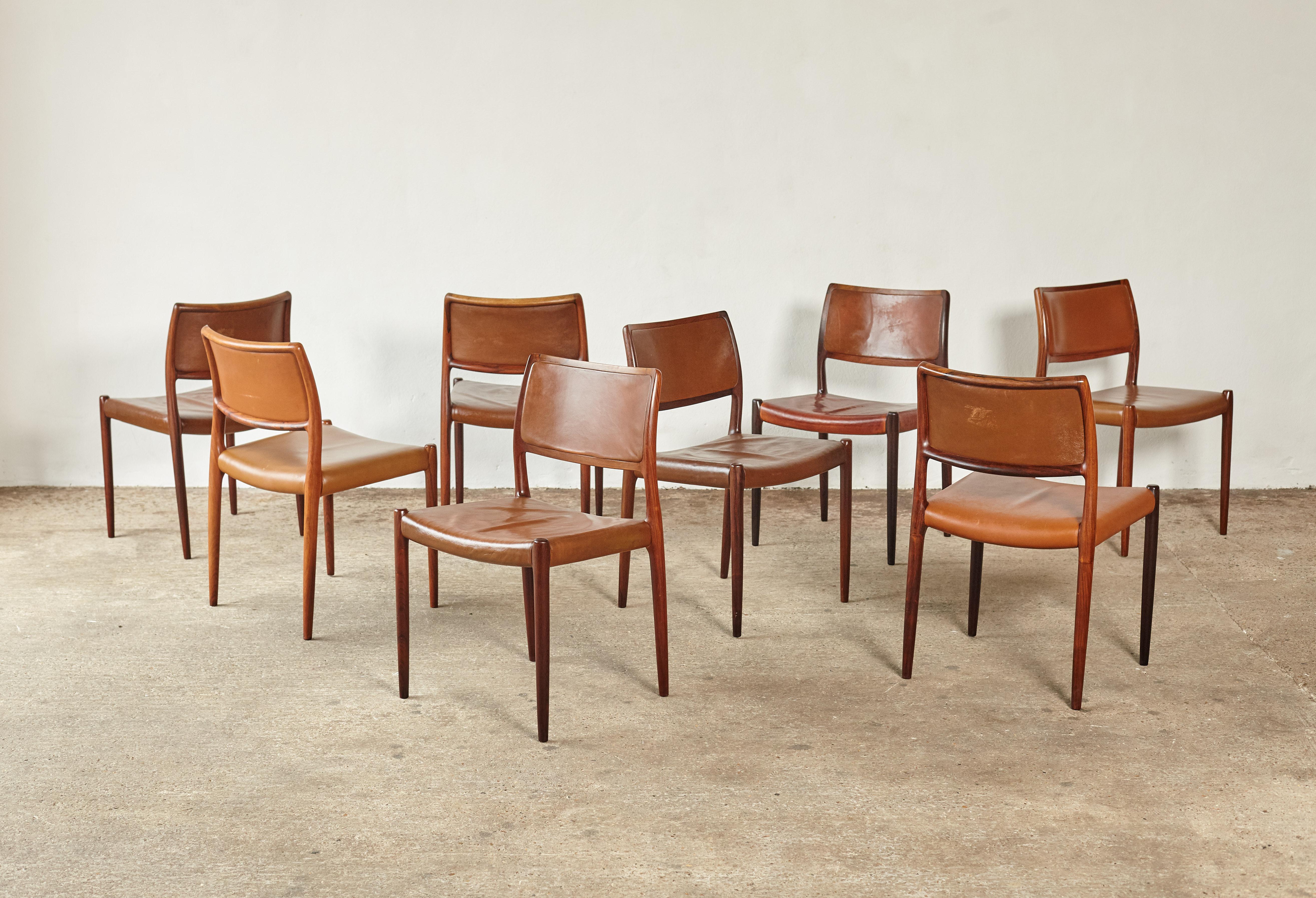 Set of eight rosewood Niels O. Møller model 80 dining chairs by J.L Møller, Denmark, 1960s. The rosewood frames are in excellent condition with a wonderful grain. Stamped with makers mark. Brown leather / vinyl seat covers are various shades of