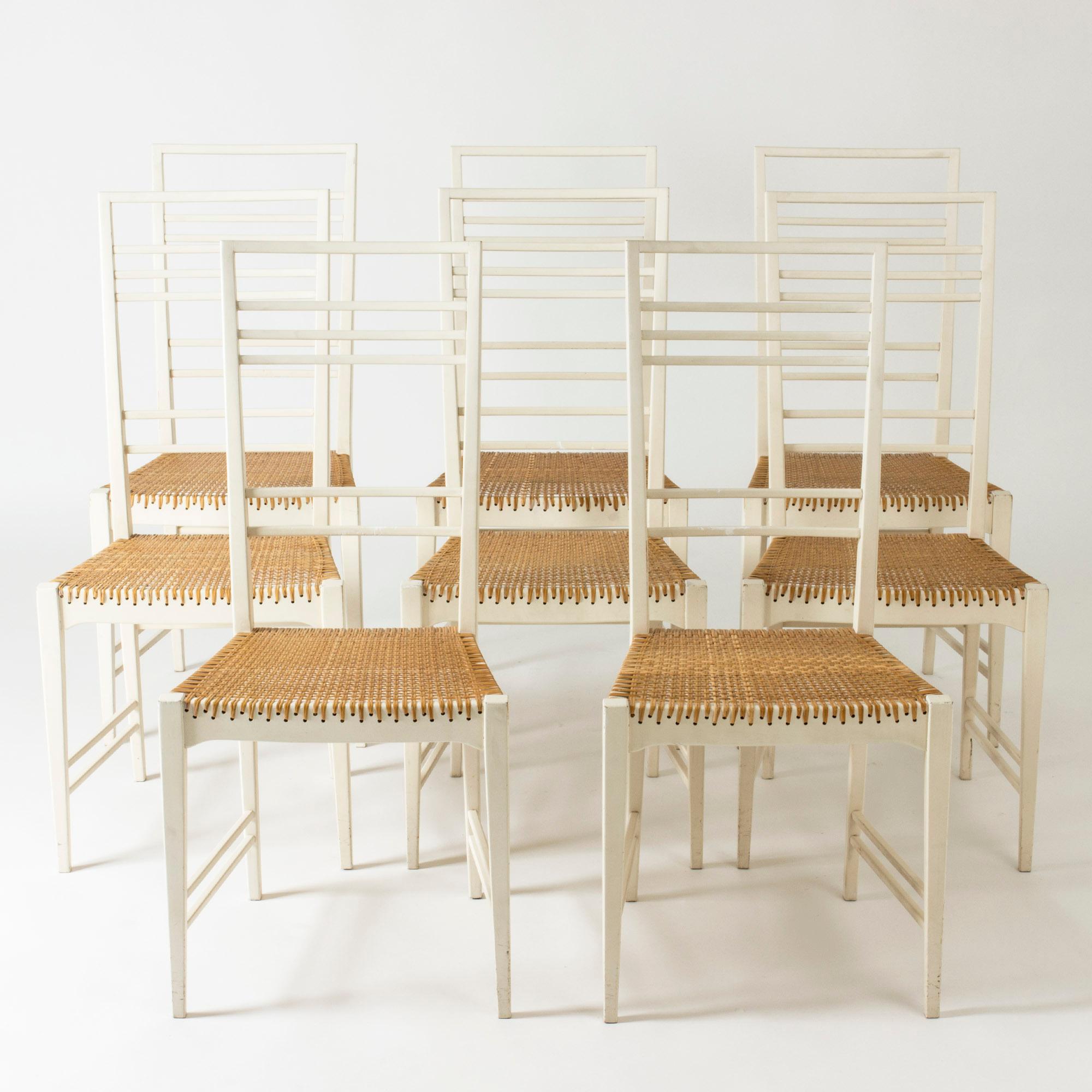 Set of eight “Poem” dining chairs by Erik Chambert, made from white lacquered wood with rattan seats.

The model was first presented in 1953, and the very fitting name for this beautiful design was coined by the art critic and then director of