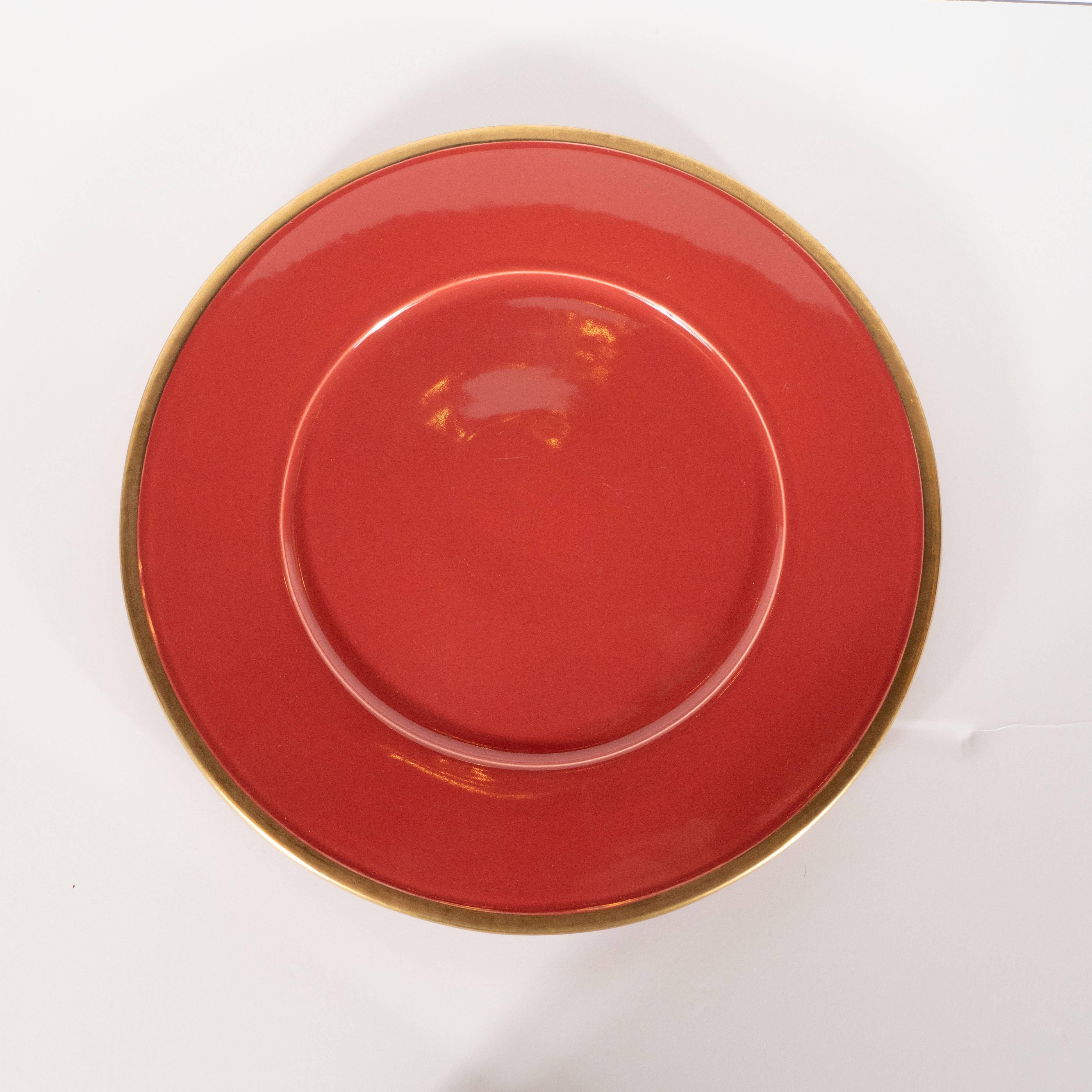 These fine modernist porcelain plates were realized by the esteemed British ceramic studio, Maryse Boxer, circa 1990. Realized in a refined carnelian, they offer slightly recessed centers and 24-karat gold rims. The bottom features two concentric