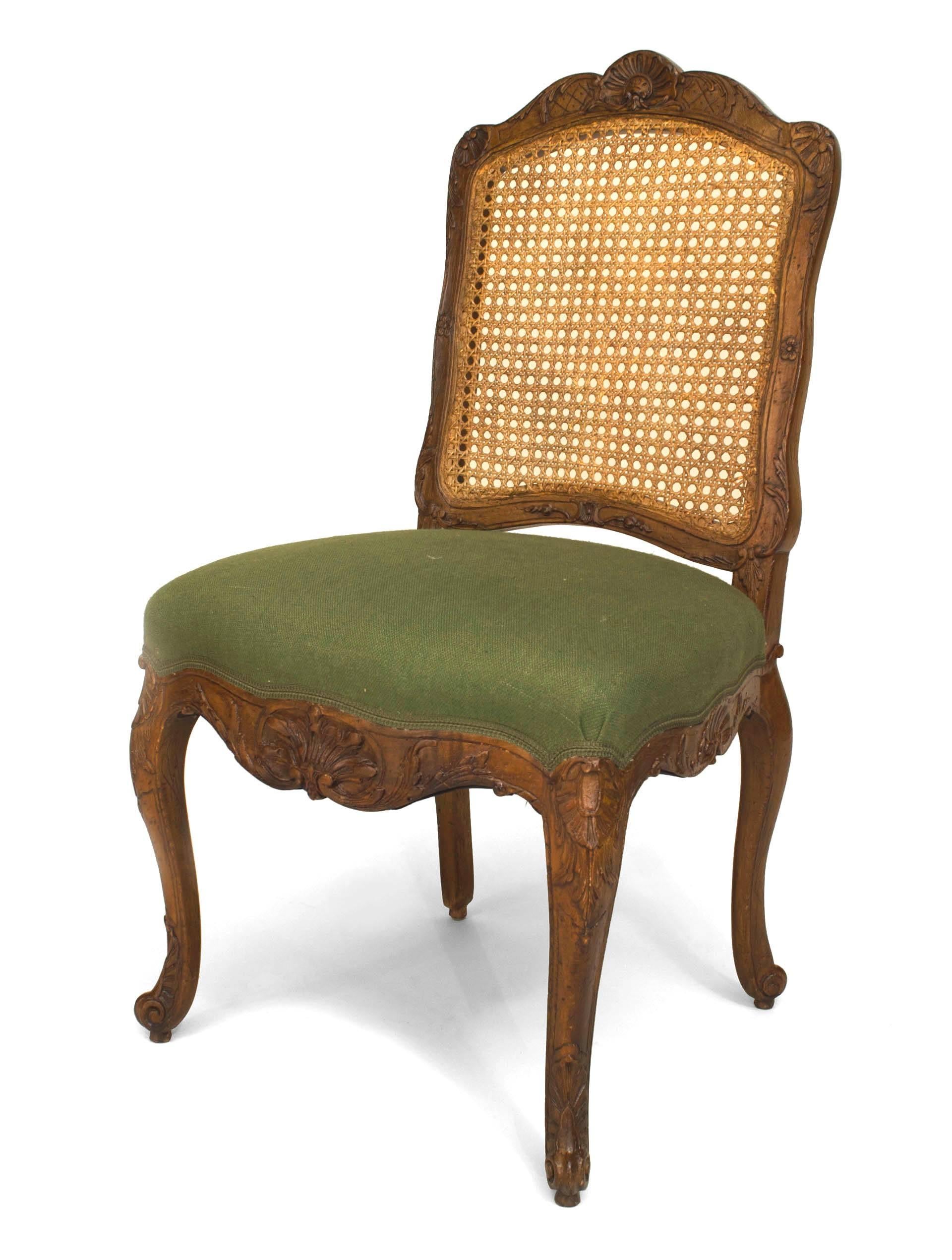 Set of 8 French Provincial Louis XV style (20th Cent) walnut carved side chairs with a shaped cane back and green upholstered seat.
