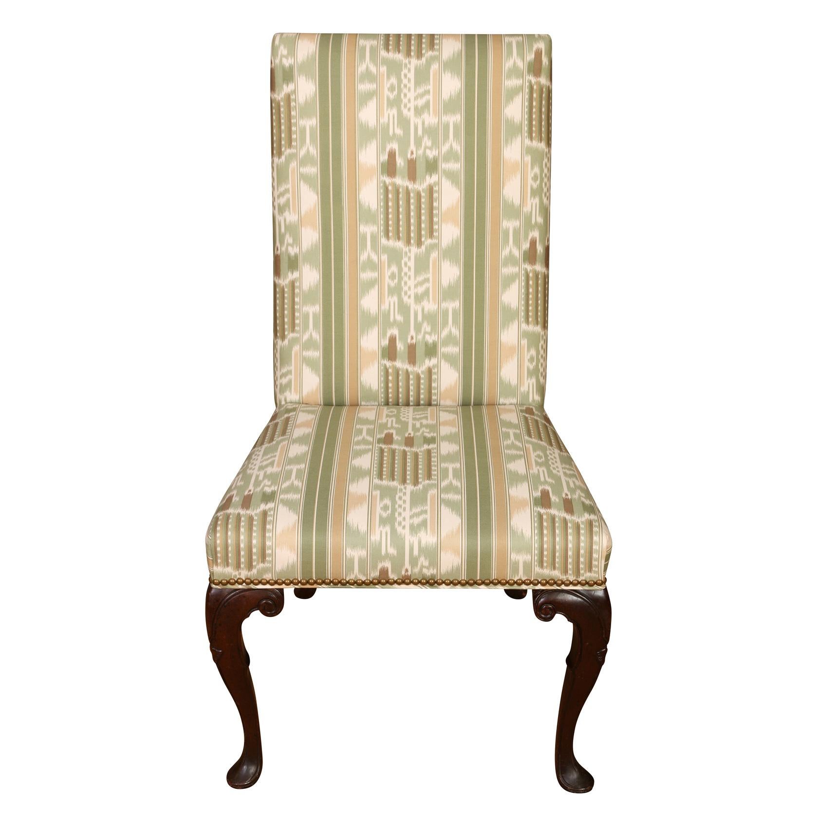 A set of eight vintage dining chairs in Queen Anne style with cabriole legs and upholstered seats and backs in green, gold and brown ikat fabric with nail head trim.