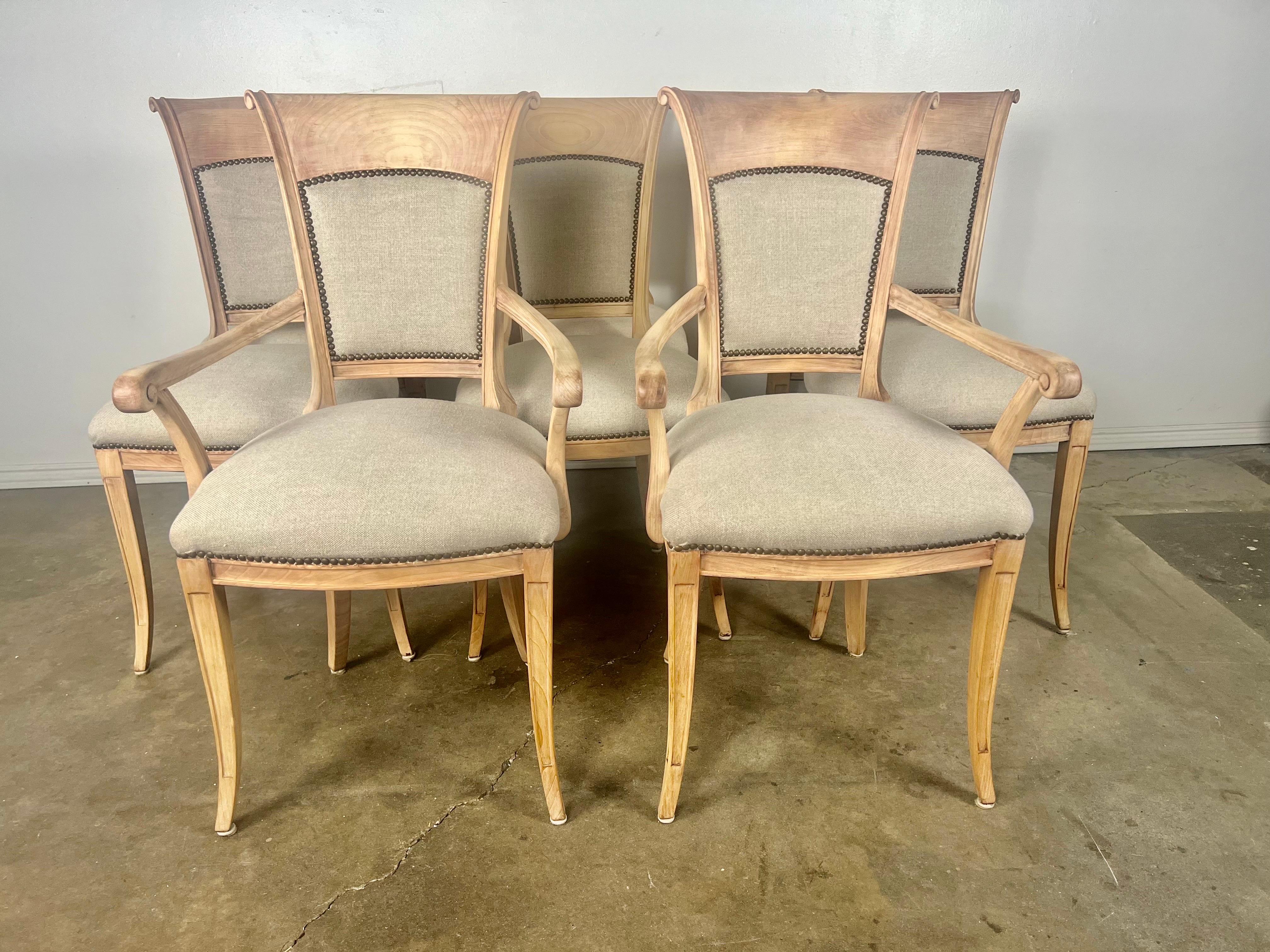 Set of eight Swedish dining chairs in a natural wood finish.  The chairs stand on four tapered legs.  They are newly upholstered in a washed Belgium linen and detailed with antique brass colored nailheads.

Size of Armchairs-38