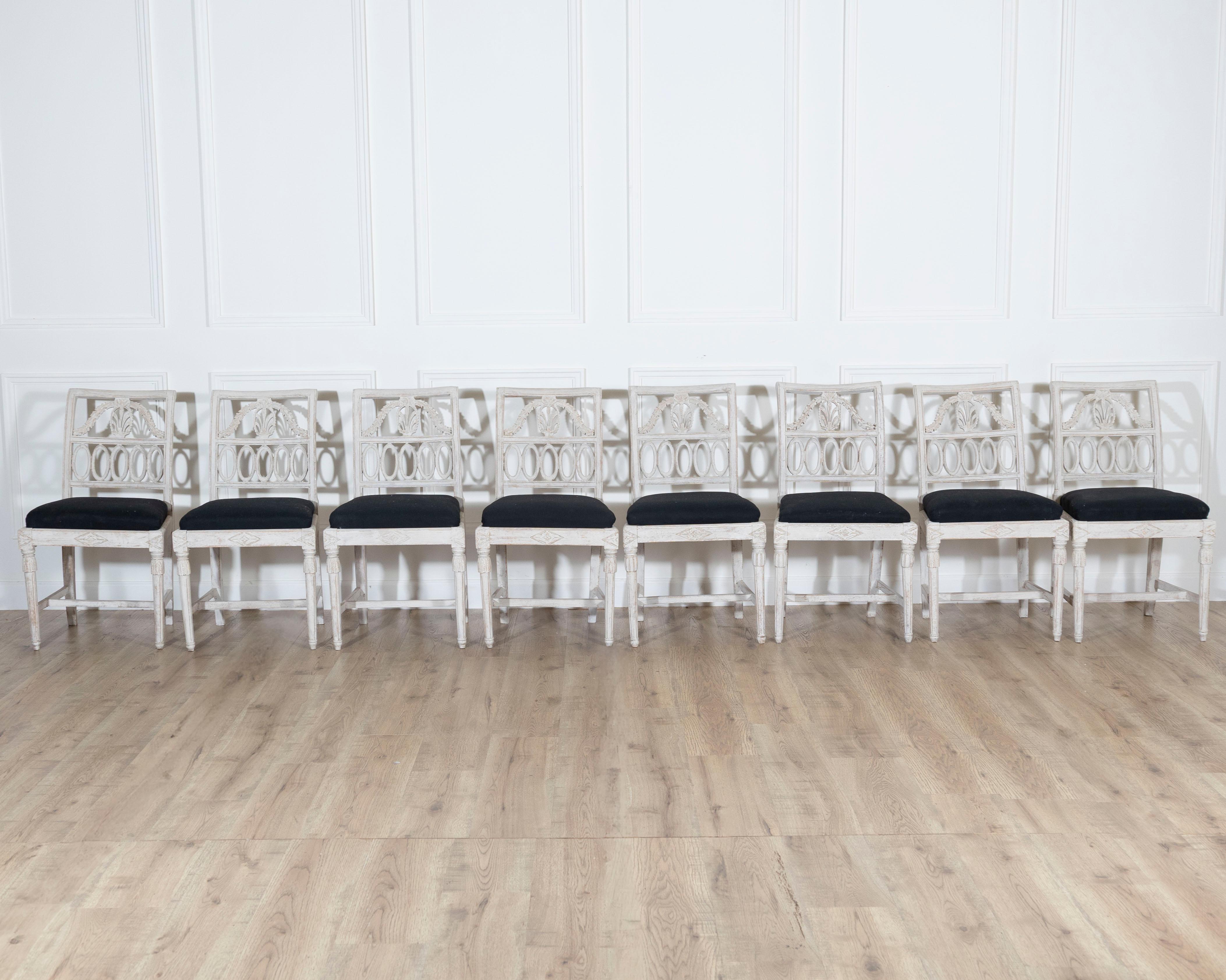 Elegant set of eight Swedish dining chairs from the Gustavian period, circa 1820, finely carved and retaining their original pale patinated finish. Each chair features an openwork backrest with neoclassical oval and sunburst motifs, reflecting the