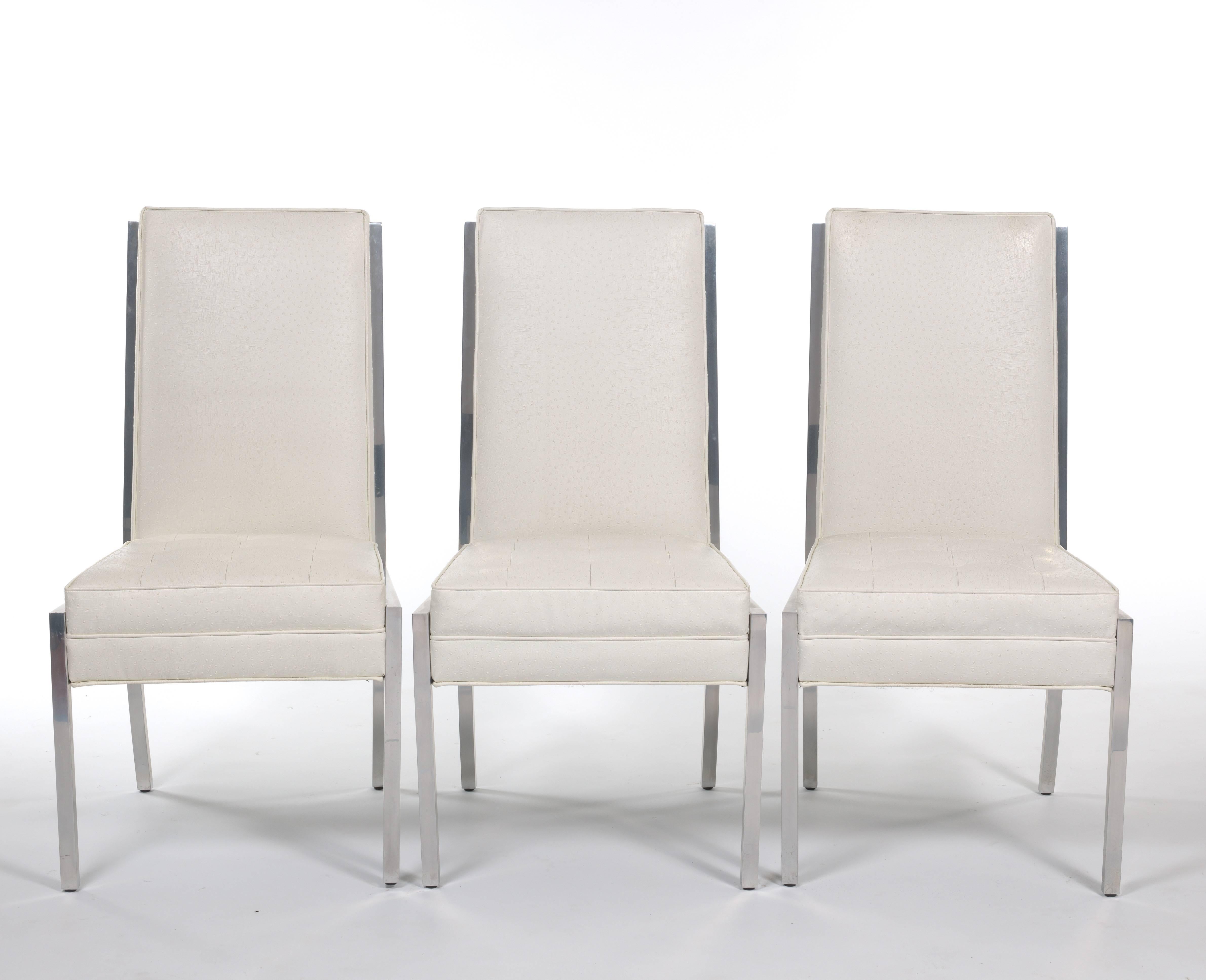 A lovely set of eight dining chairs that will make you feel like you are sitting in the height of 1970s glamour. Two armchairs and six side chairs covered in white faux ostrich leather with tufted seats and chrome frames. These chairs have elegant