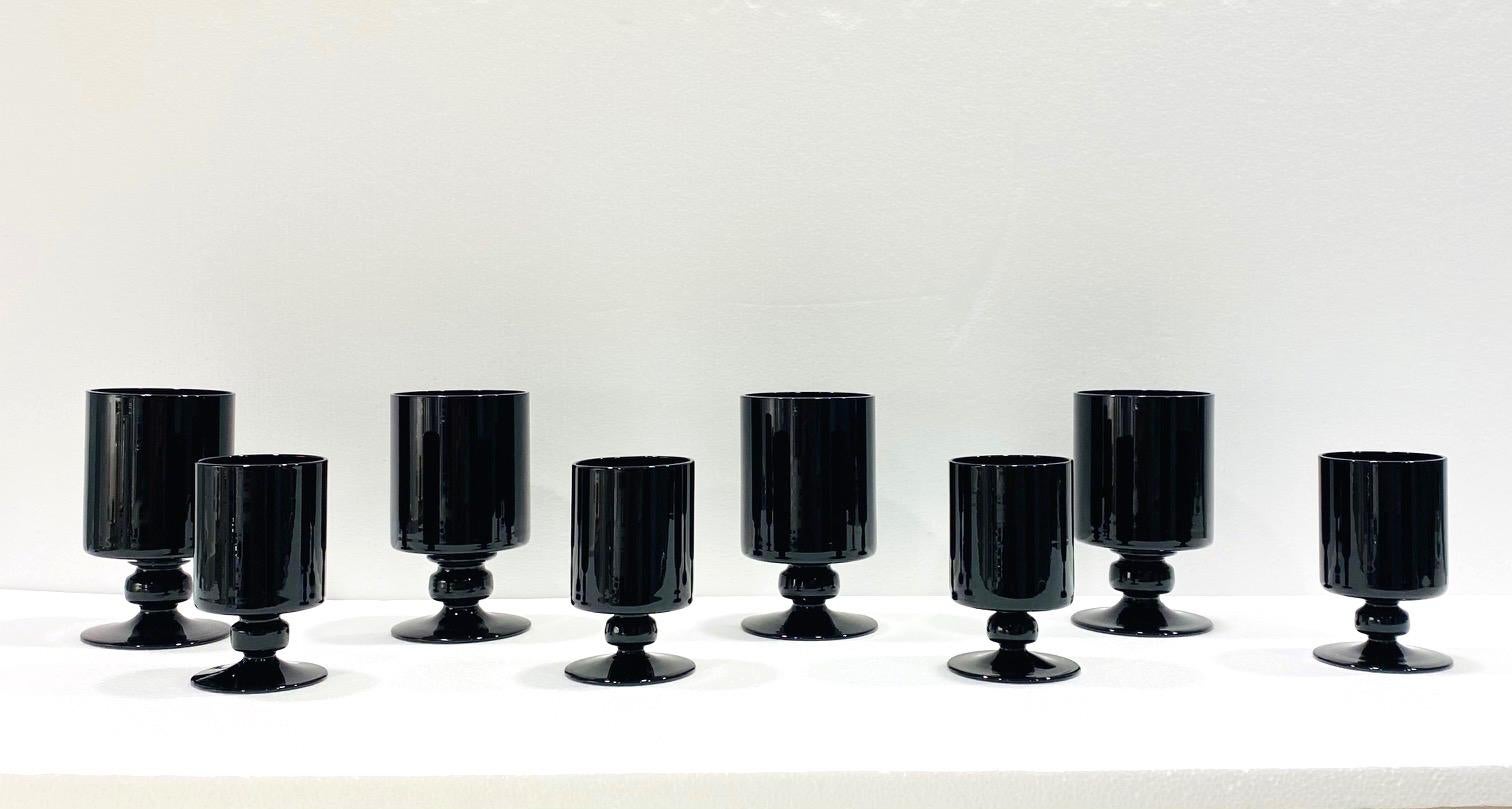Vintage set of blown glass stemware in black opaque crystal. Hollywood Regency style set includes four wine glasses and four larger water goblets. The glasses feature cylinder bowls with short stylized stems and solid weight. Makes a chic addition