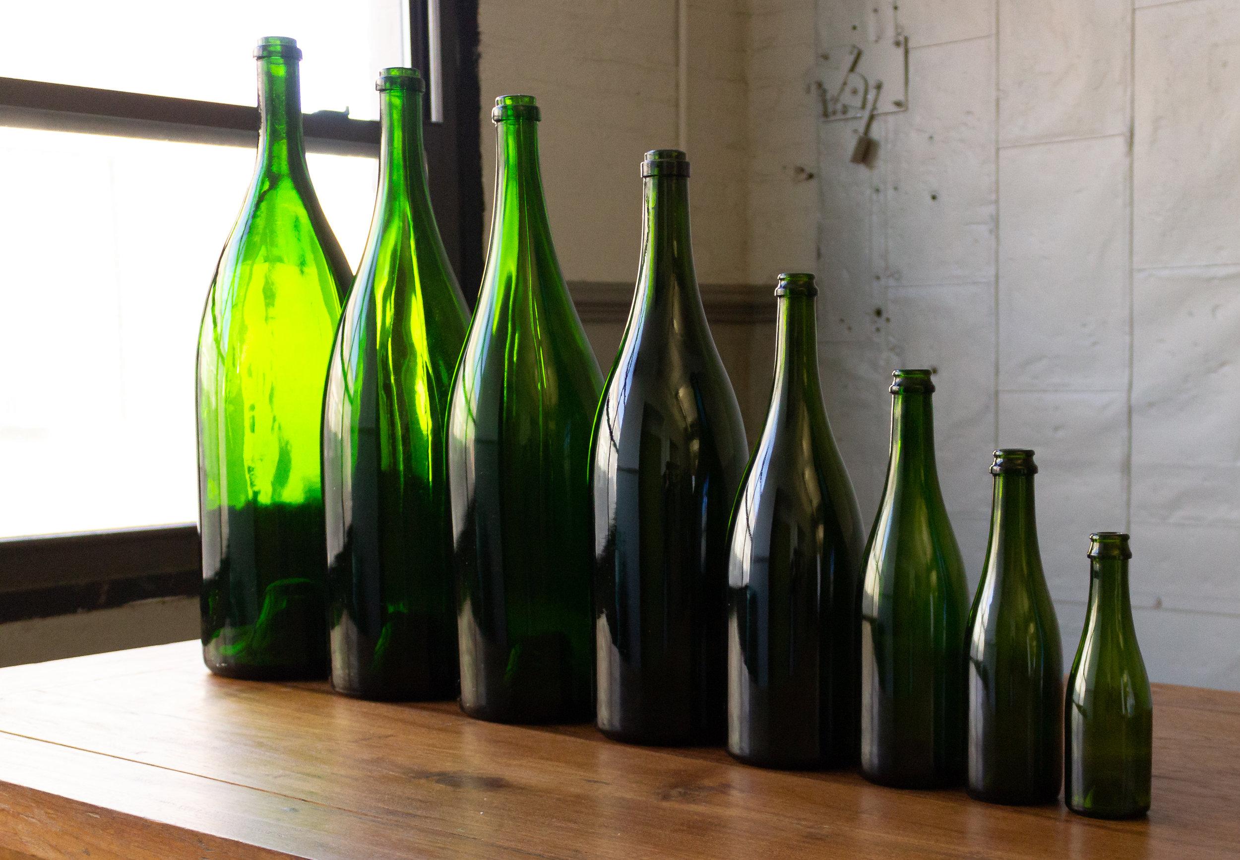 This set of eight vintage French champagne bottles from the 1920s offers a unique charm. Their sizes vary, ranging from 7.5 inches to 25 inches in height, allowing for an appealing visual display. Each bottle is in very good vintage condition and