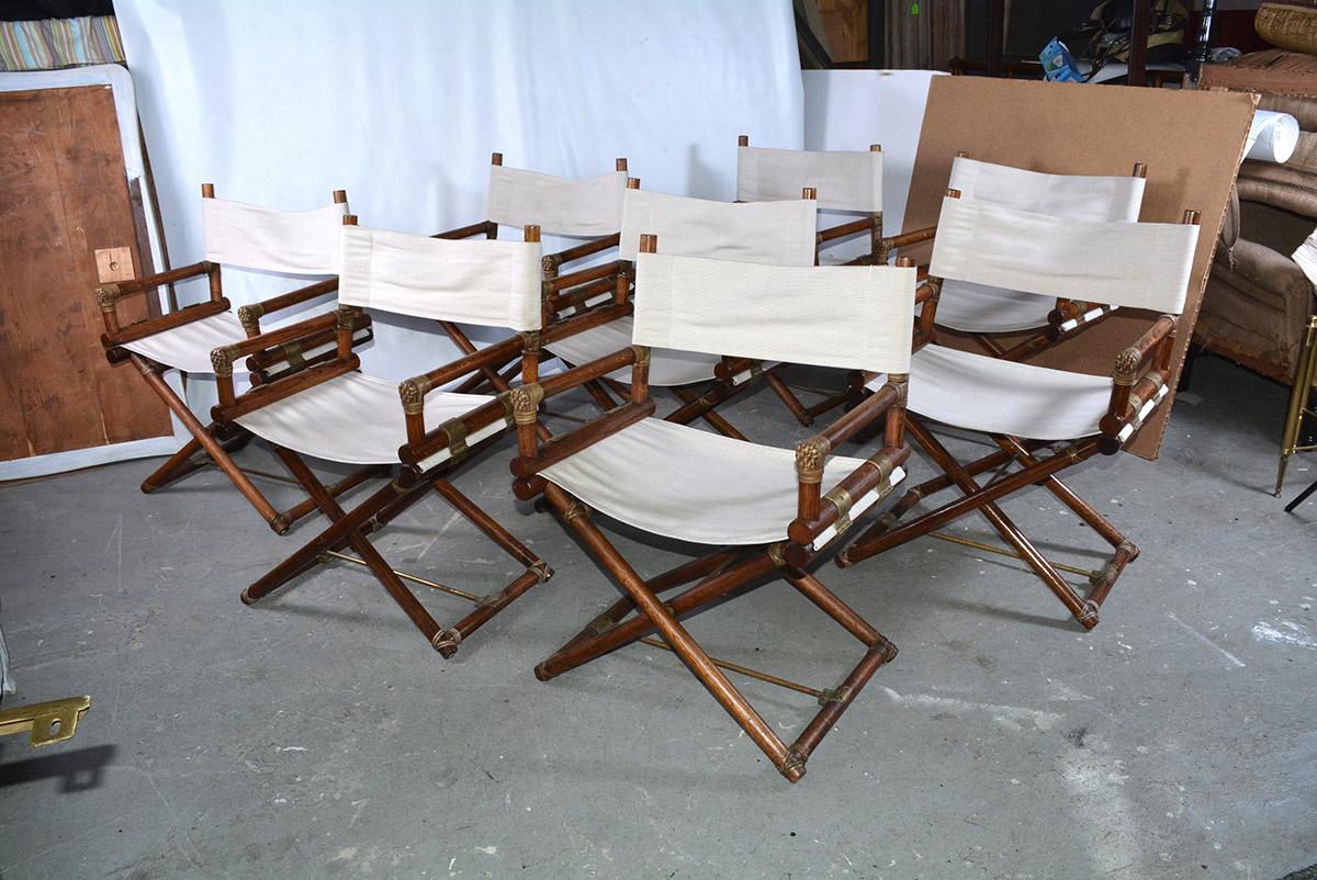 Set of 8 stylish vintage McGuire Campaign / Director style dining chairs. Carved wood frames with fabric seats and backs, metal hardware. Classic English Campaign form chairs. Each measures 32 x 24 x 19, fabric need cleaning or replacement. We can