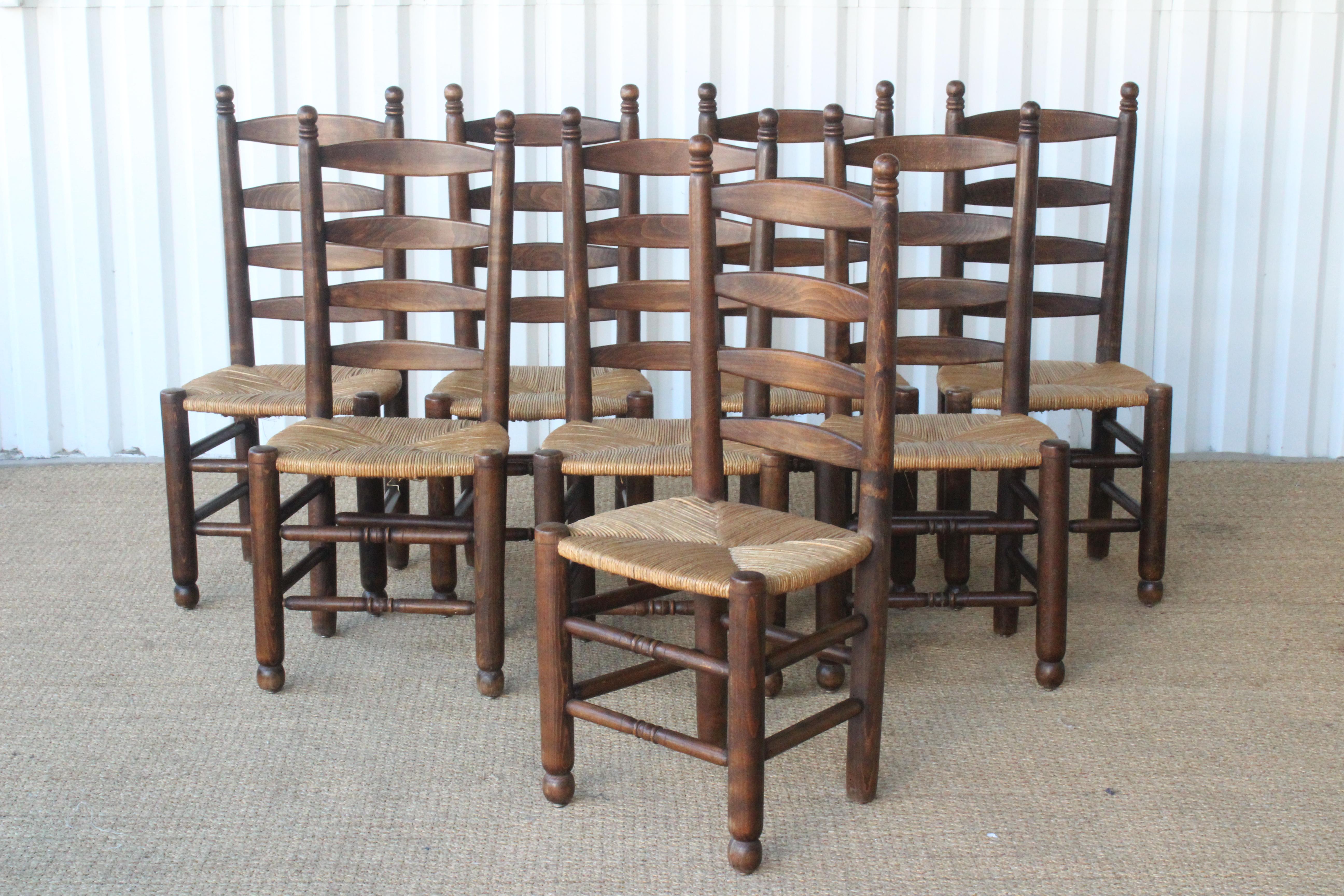 Set of eight rustic dining chairs made of oak with woven rush seats. made in France in the 1960s. The oak frames are in the original dark stained finish. The rush seats are original and in excellent condition. Sold only as a set of eight.