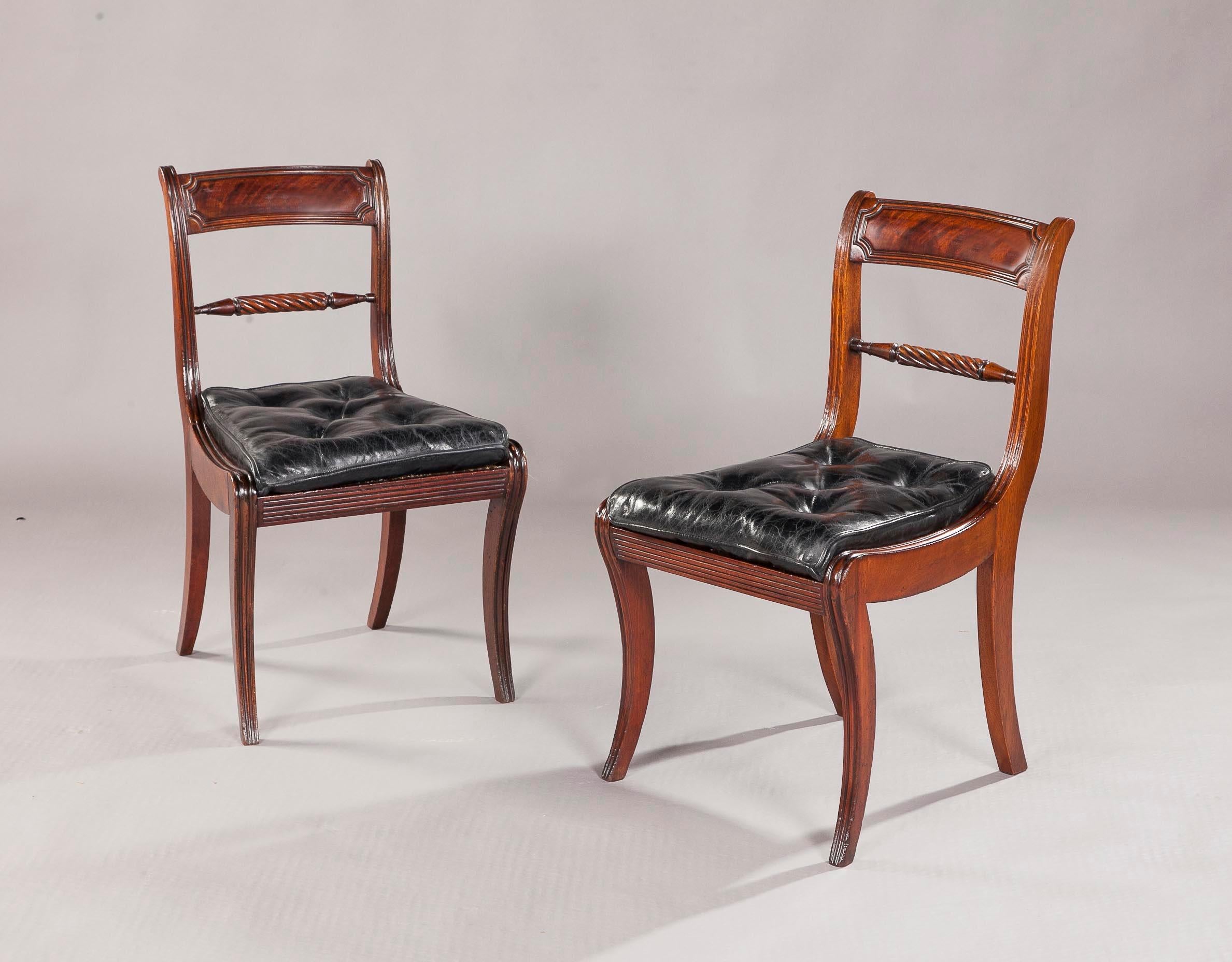 A fine set of eighteen regency mahogany sabre leg dining chairs, the reeded panel backs above a central reeded splat, with bergre seats, covered in black hide, on reeded sabre legs, good original colour and patina throughout.