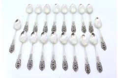 Set of eighteen silver dessert spoons with floral reliefs on the handles