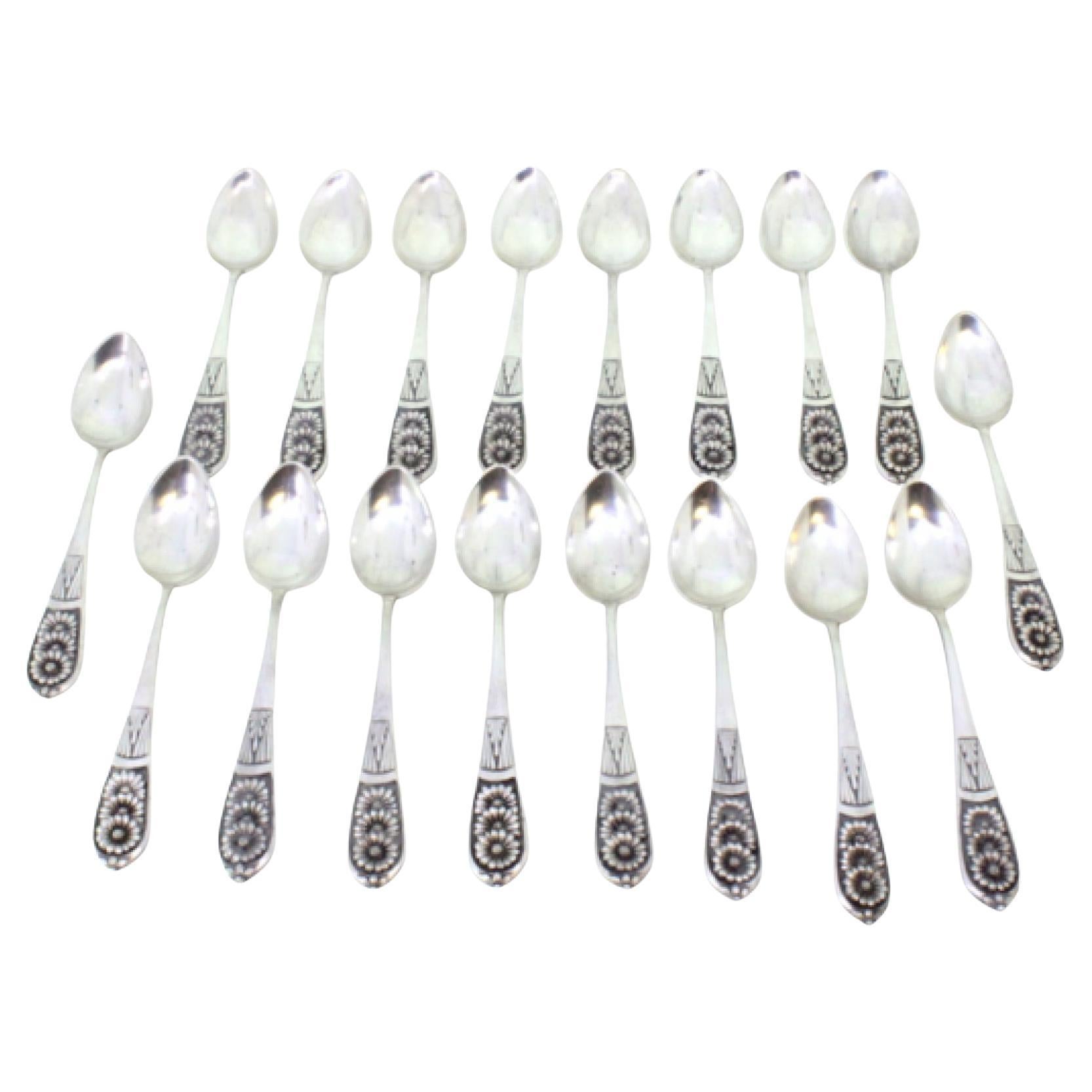 Set of eighteen silver dessert spoons with floral reliefs on the handles