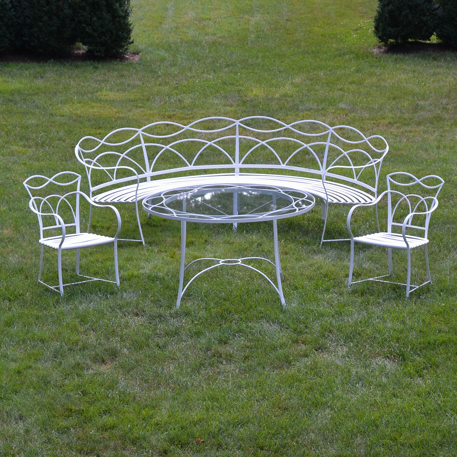 A suite of wrought-iron furniture manufactured by Leinfelder & Sons of Lacrosse, WI, comprised of one curved settee, one round dining table, and two armchairs, circa 1930. Table is 29 ins. high and 48 ins. in diameter. Curved bench is 32 ins. high,