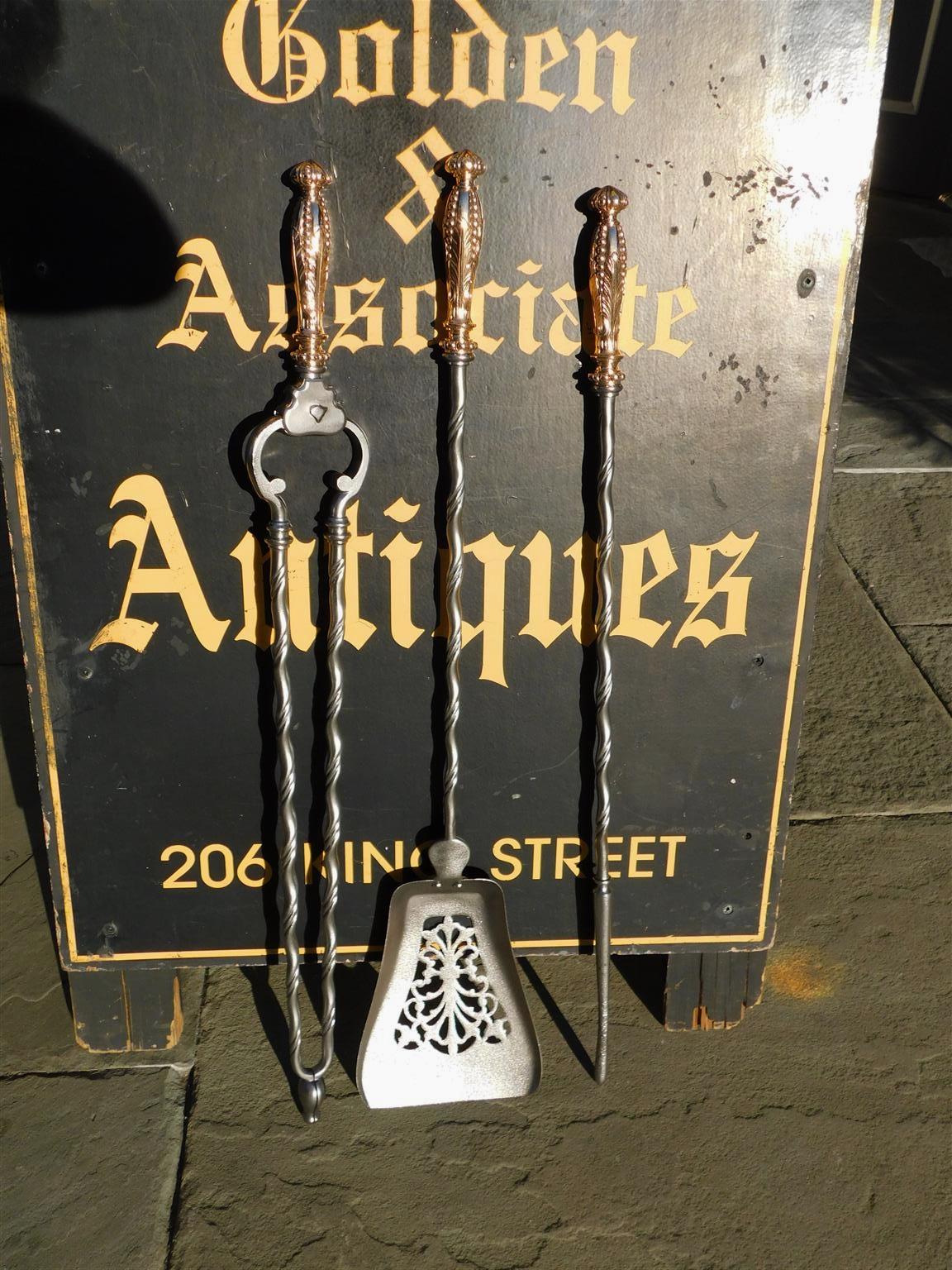 Ensemble d'outils à feu anglais en laiton et acier poli, décorés de feuillages percés et de spirales, début du XIXe siècle. L'ensemble comprend une pelle, une pince et un tisonnier.