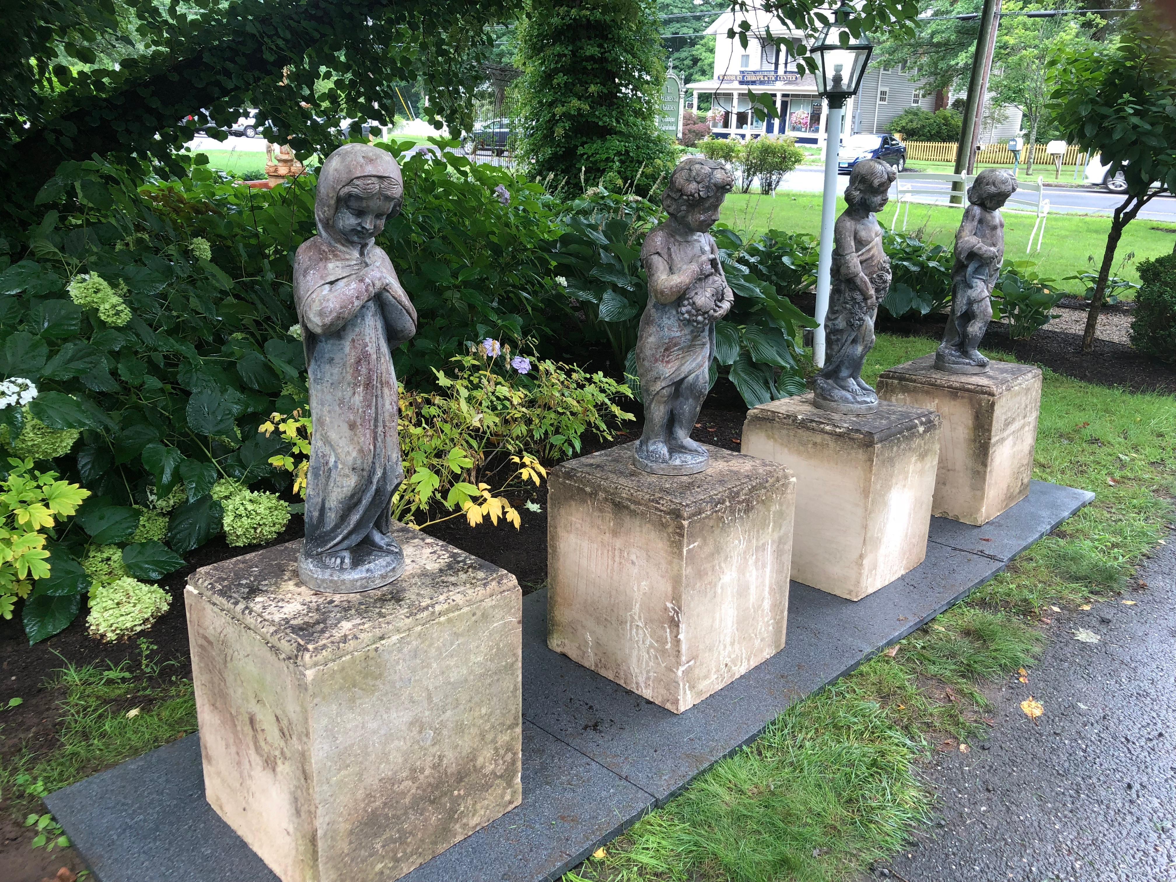 A spectacular set of four lead figures, each representing a different season, are raised up on large plinth blocks of limestone with a beveled top edge. From Oprah Winfrey's personal collection, where they once graced her Montecito estate, they