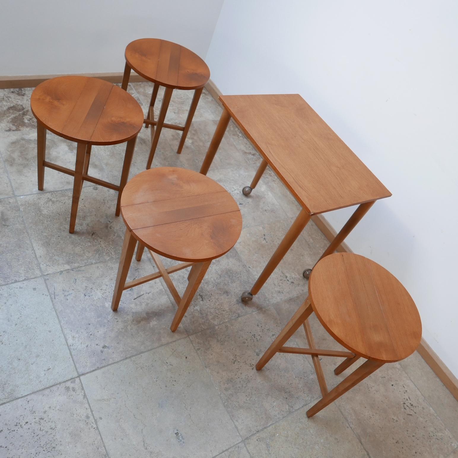 A set of cocktail tables / side tables nesting very cleverly in a larger table. 

Great fun and functional. 

Likely English but perhaps Danish, c1950s. 

Ideally one would remove the fairly horrible wheels but we have left them on as an