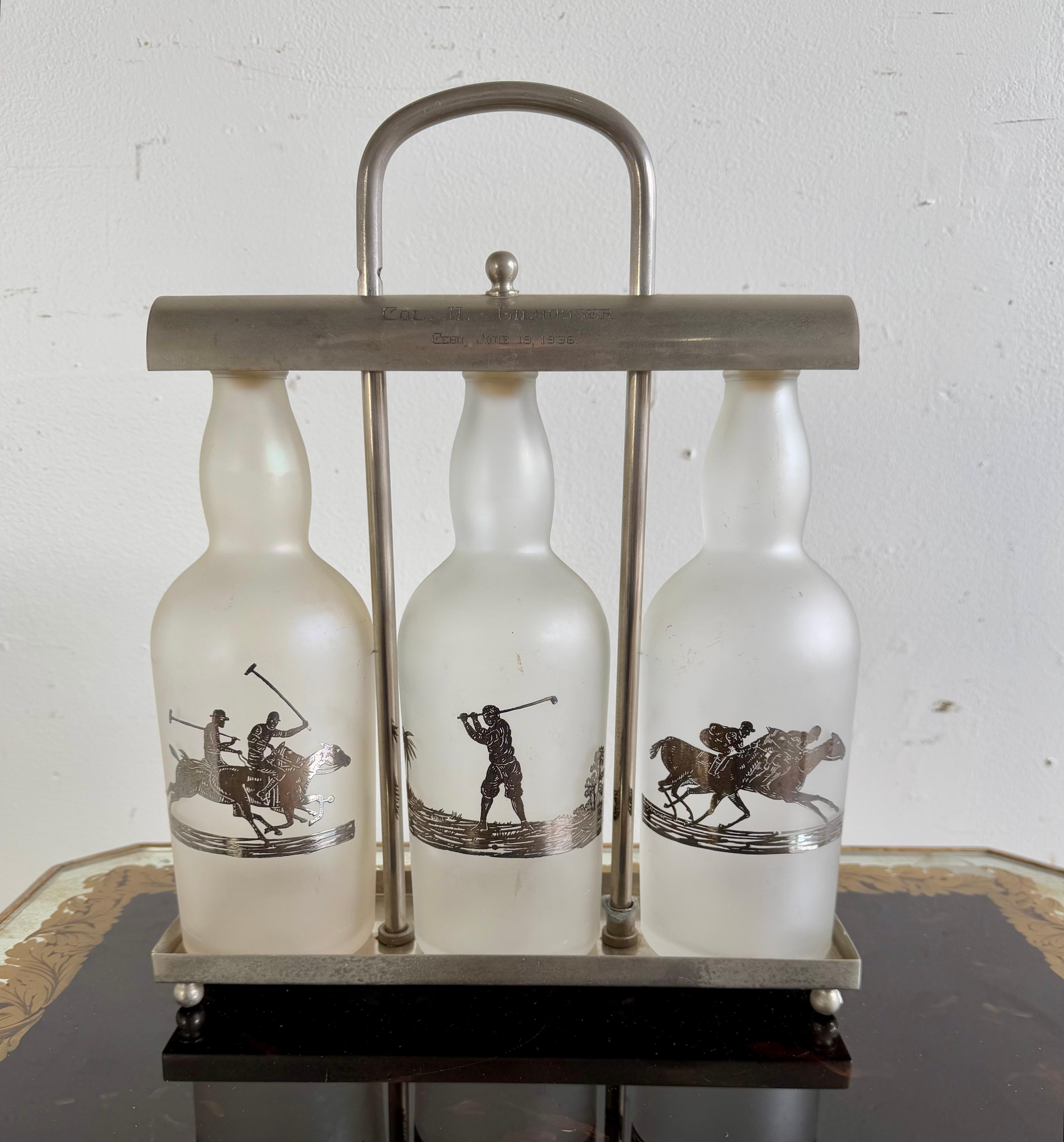 Vintage set of three frosted glass bottles held in a stainless steel rack (tantalus) with a handle at the top.  Each bottle features a silver image of polo players in action.  The designs depict players on horseback, swinging mallets, likely in the
