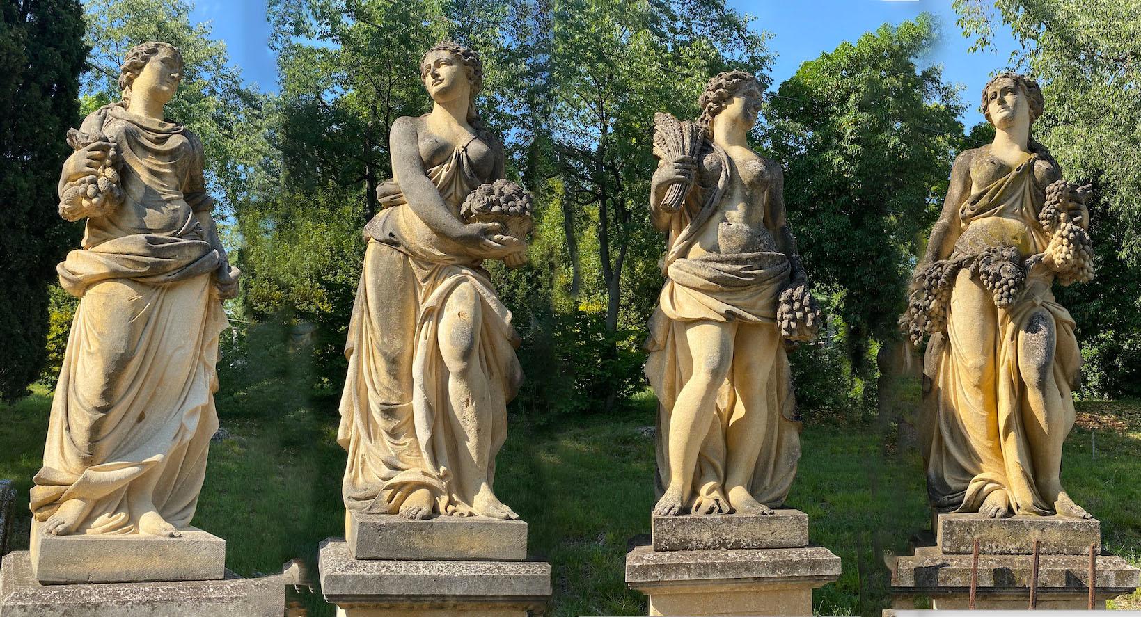 Monumental classically draped finely carved standing female figures and their distinguishing symbols on a square base. 
Autumn, winter, spring and summer. 
The sculptures has developed a great patina from several years of exposure in a lush