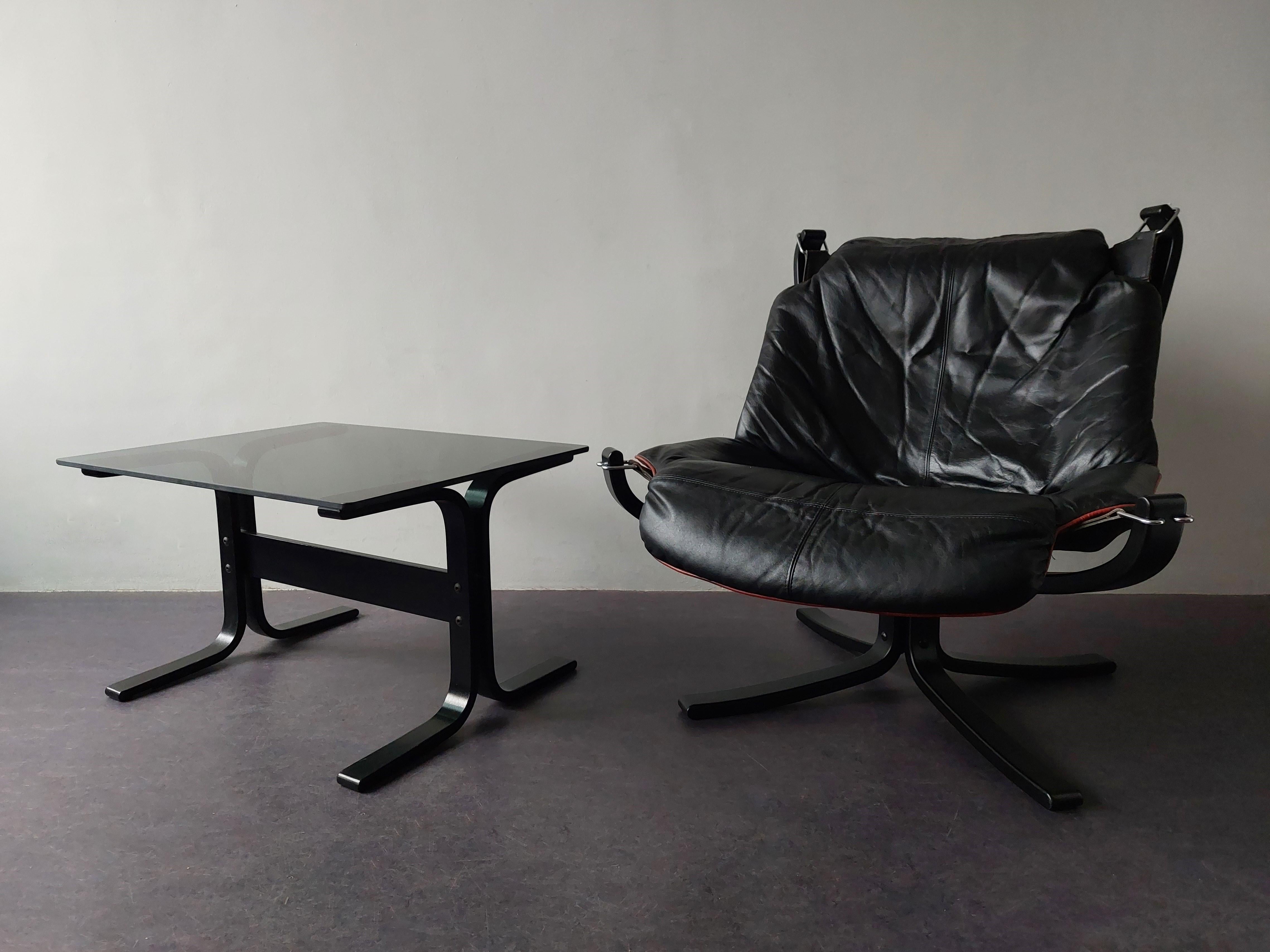 The Falcon chair was designed by Sigurd Ressell for Vatne Møbler in 1970 in Norway. A beautiful low back relaxing lounge chair. It has a black base made of bended plywood and a supple black leather with red trim seat. The seat is mounted on leather