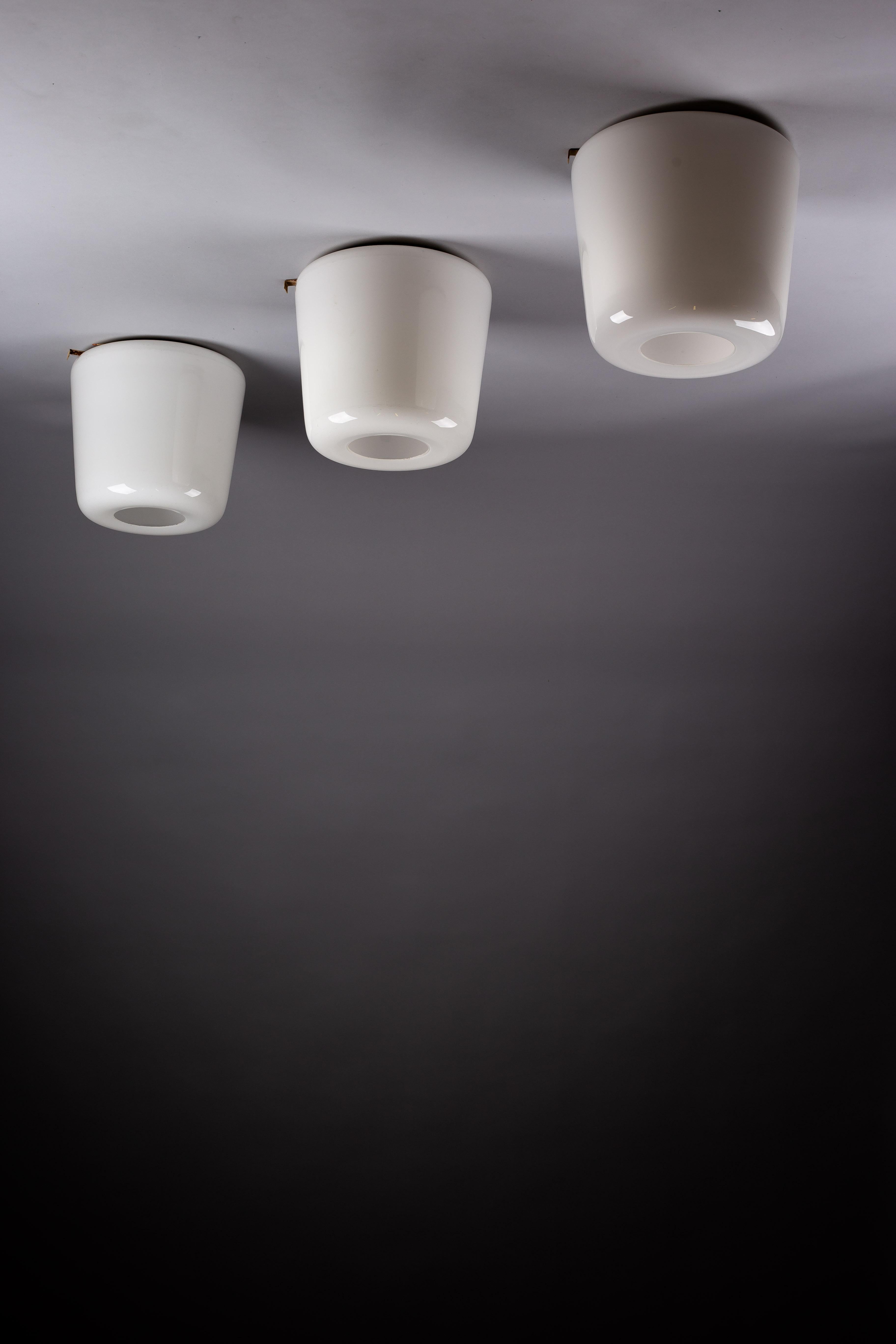 Elevate your home decor with this exquisite set of Finnish mid-century modern opaline glass flush mounts. These sophisticated flush mounts feature a unique design with a whole in the middle letting light out, creating a captivating ambiance in any