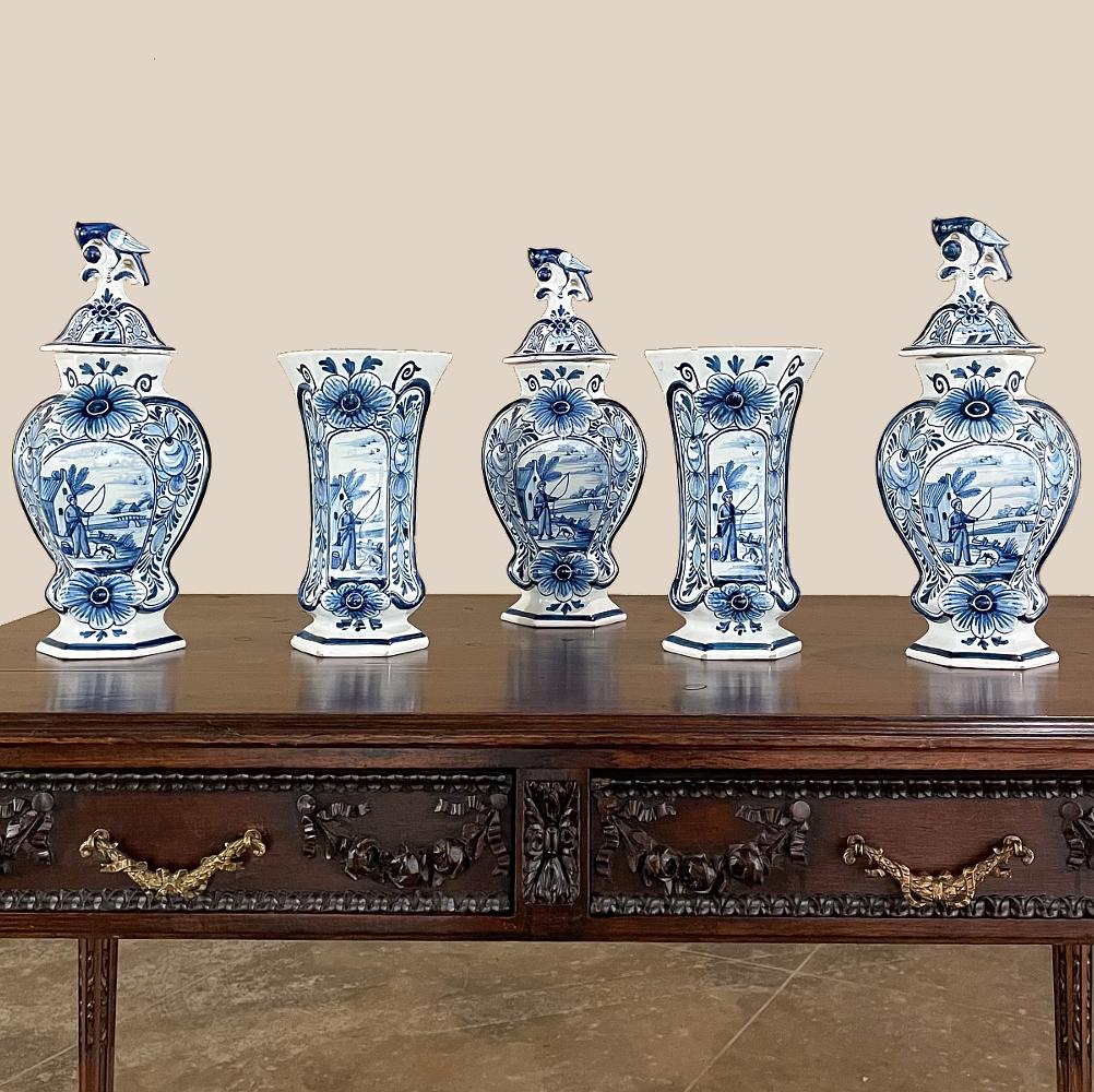Ein Satz von fünf handbemalten Delft-Vasen aus dem 19. Jahrhundert, darunter 3 Urnen mit Deckel, die auch als Garnitur bezeichnet werden, erhebt die blau-weiße Kunstform zu einem besonderen Ort, da sie alle von einem Künstler mit passenden Motiven