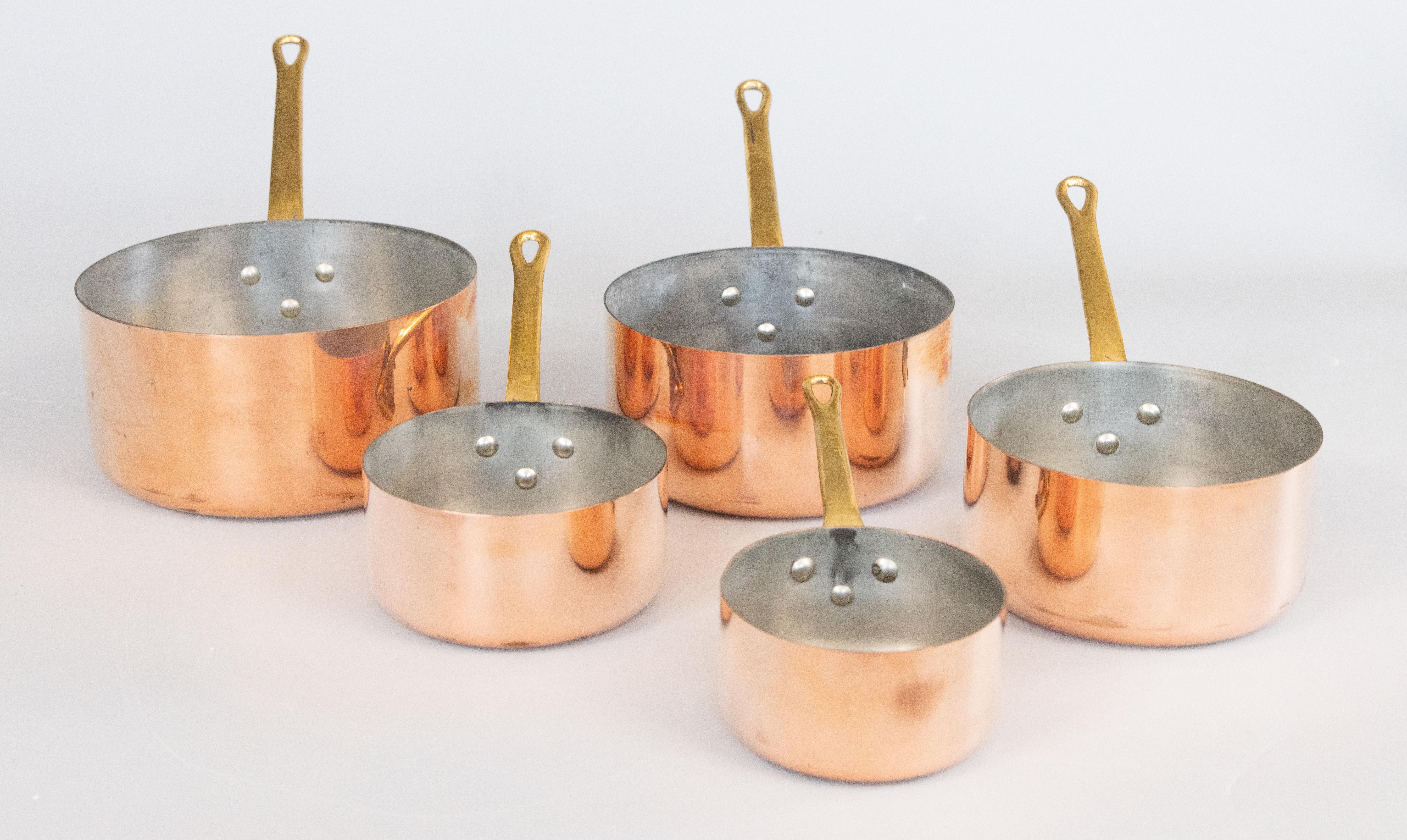 Uno splendido set antico di cinque pentole e padelle in rame graduate francesi. I bei manici lunghi sono in ottone massiccio con rivetti e i vasi presentano la superficie e la patina originali. Perfetto per l'arredamento e la cucina French