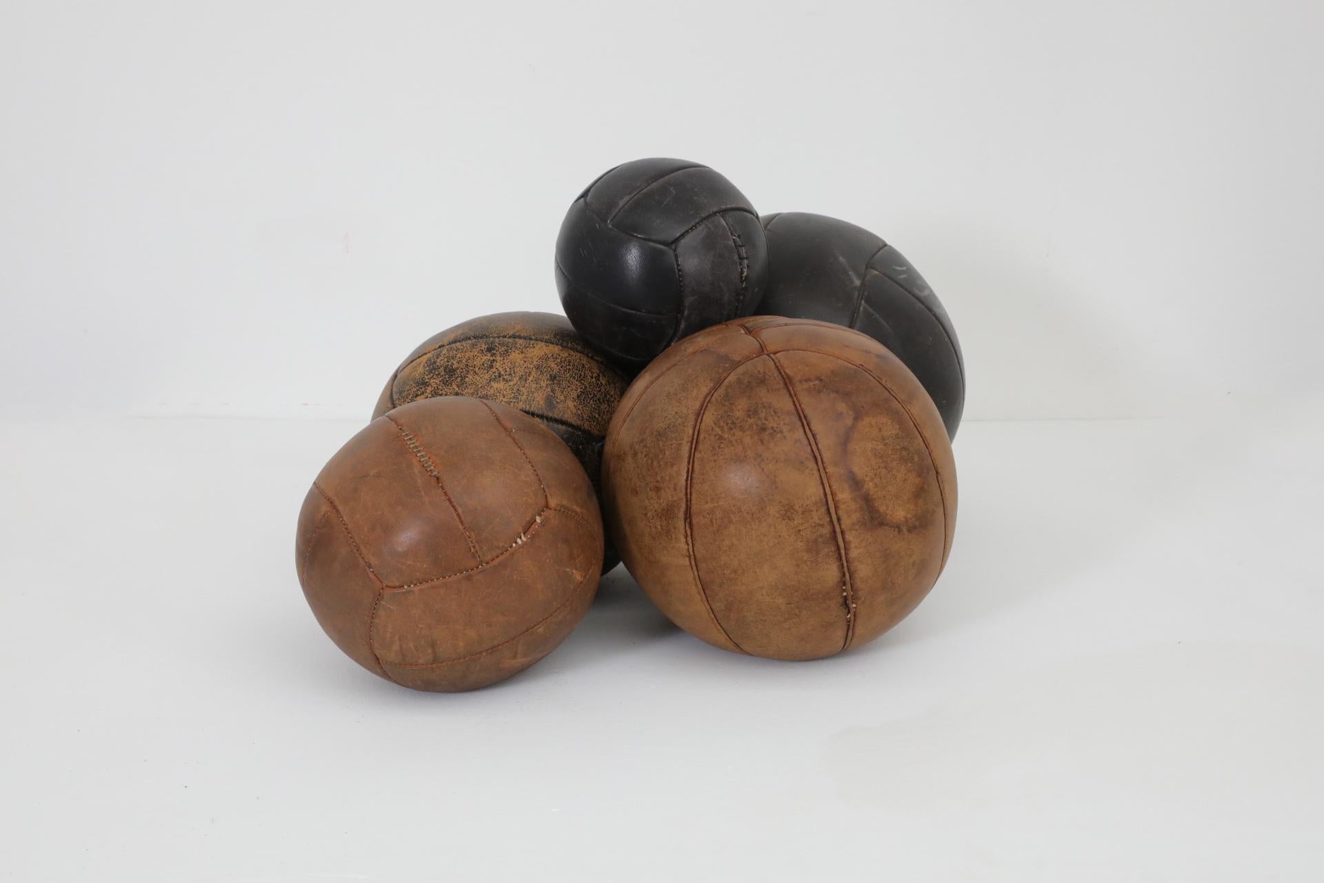 Juego de cinco balones medicinales gimnásticos de cuero de los años 50 de tamaños y tonos de cuero surtidos. Cada balón tiene cuero original con desgaste y pátina visibles, reparaciones hechas en las costuras. Apx. Los diámetros y pesos son los