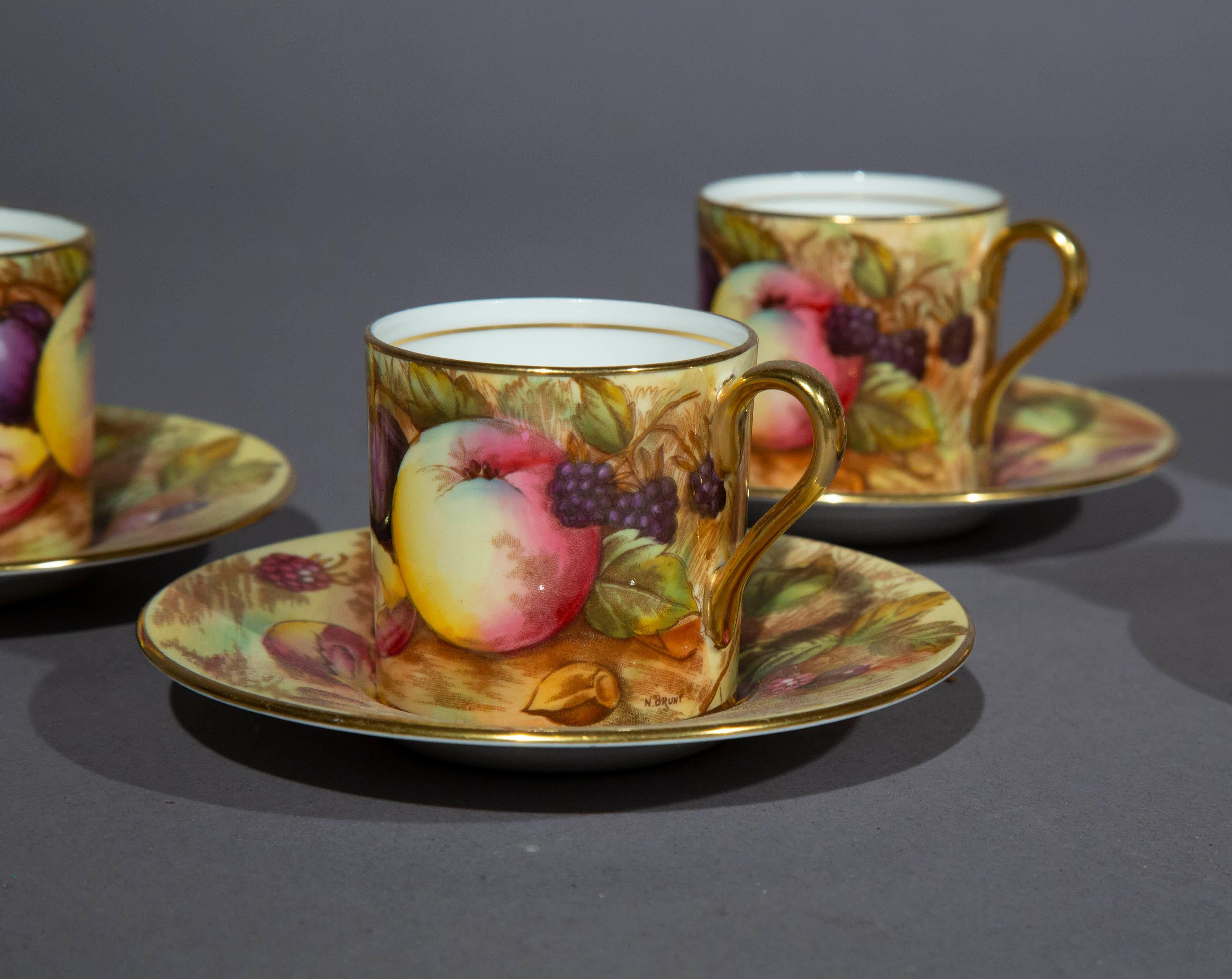 Ensemble de cinq tasses à café et soucoupes en porcelaine, motif Fruit Orchard, décoré par Nancy Brunt (active 1935-1975) pour Aynsley, Angleterre
Circa 1950's

Elégantes petites boîtes à café et soucoupes assorties, au motif coloré de fruits,