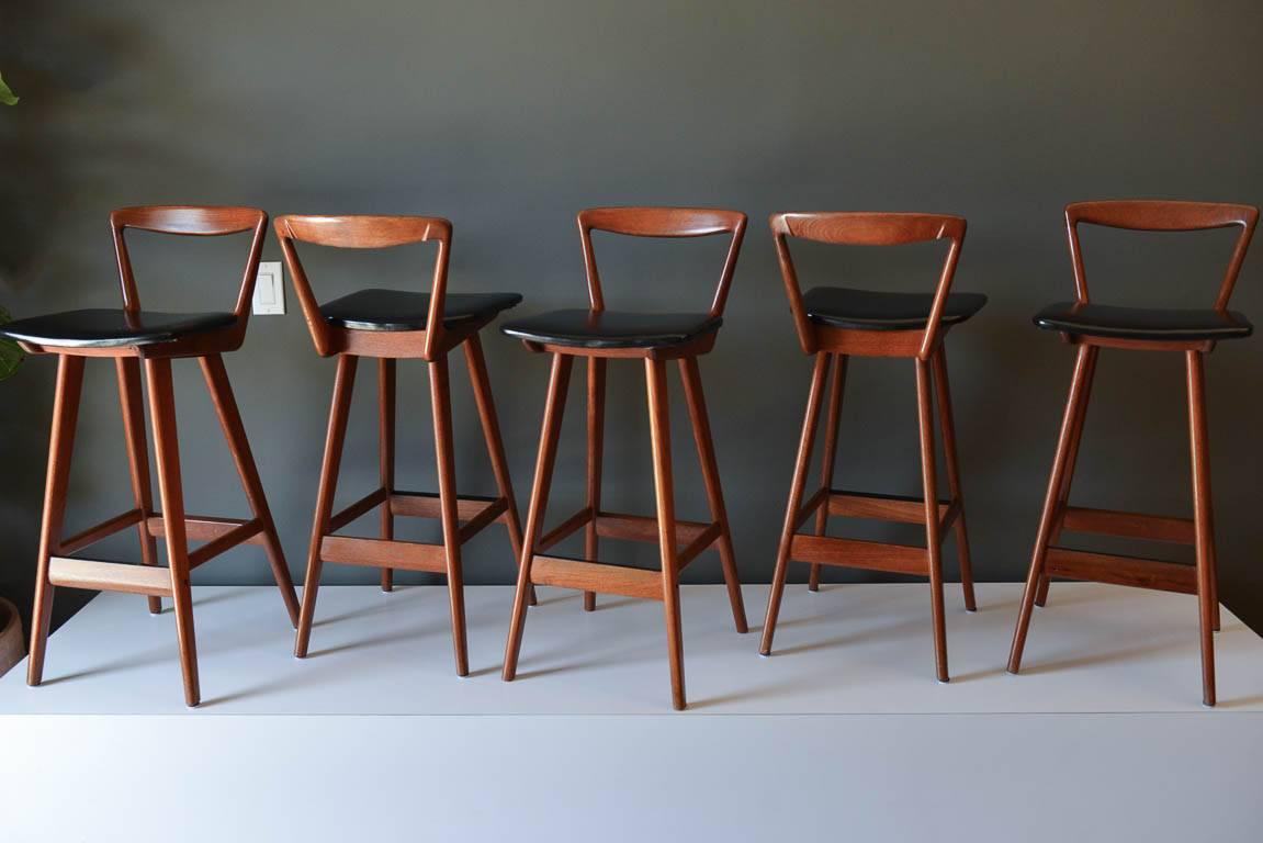 Set of five barstools by Henry Rosengren Hansen, circa 1960. Teak with original black seats. Excellent vintage condition. These are counter height stools. Offered by The Modern Vault, Costa Mesa, CA. 

Seat height measures 26.75