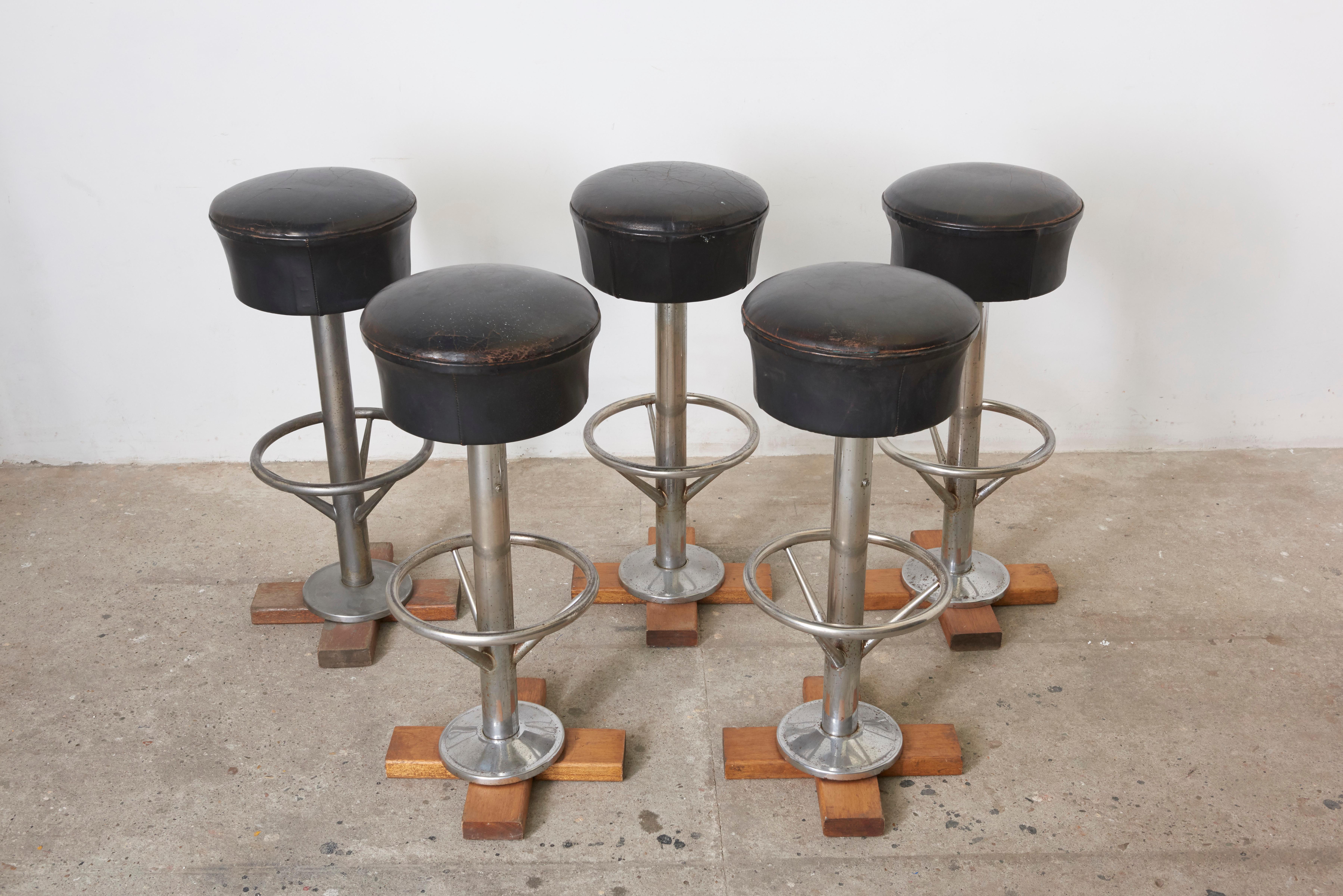Set of five bar stools with revolving sit in original leather and beautiful patina, the base is chromed steel.
These bar stools were used to be on a former boat so they could also be screwed to a wooden floor. The wooden cross can be removed at the