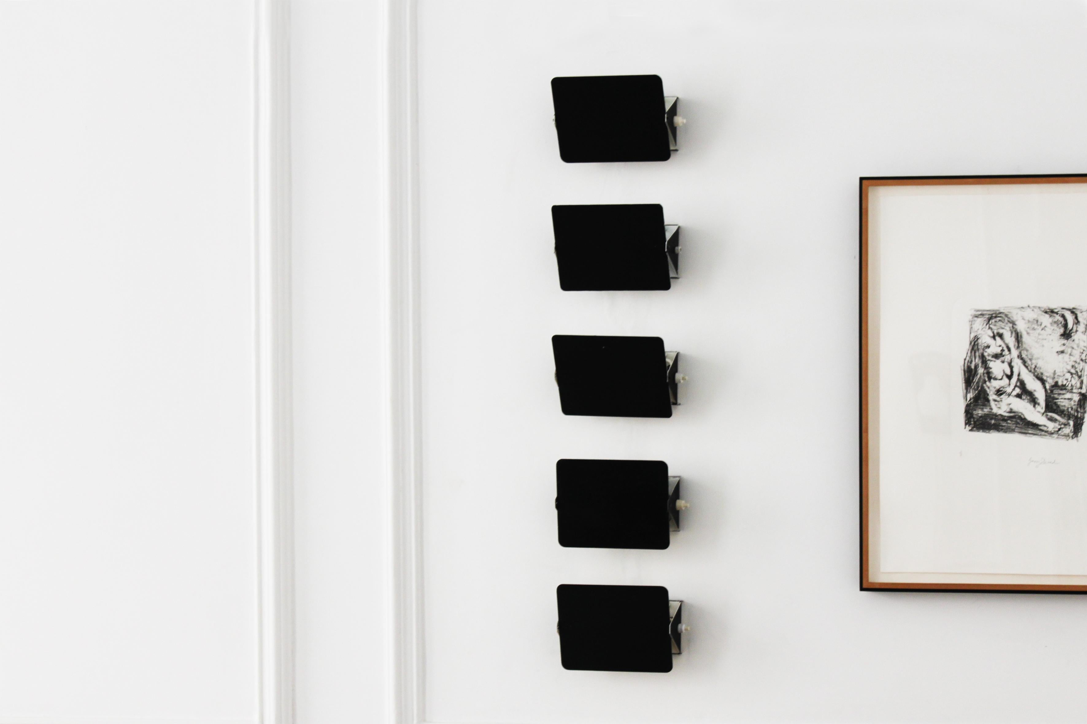 An original set of the iconic rectangular CP1 wall sconces by the legendary 20th century designer Charlotte Perriand. The black lacquered swiveling front plate conceals the light bulb and allows the light to be angled and directed. Can be installed